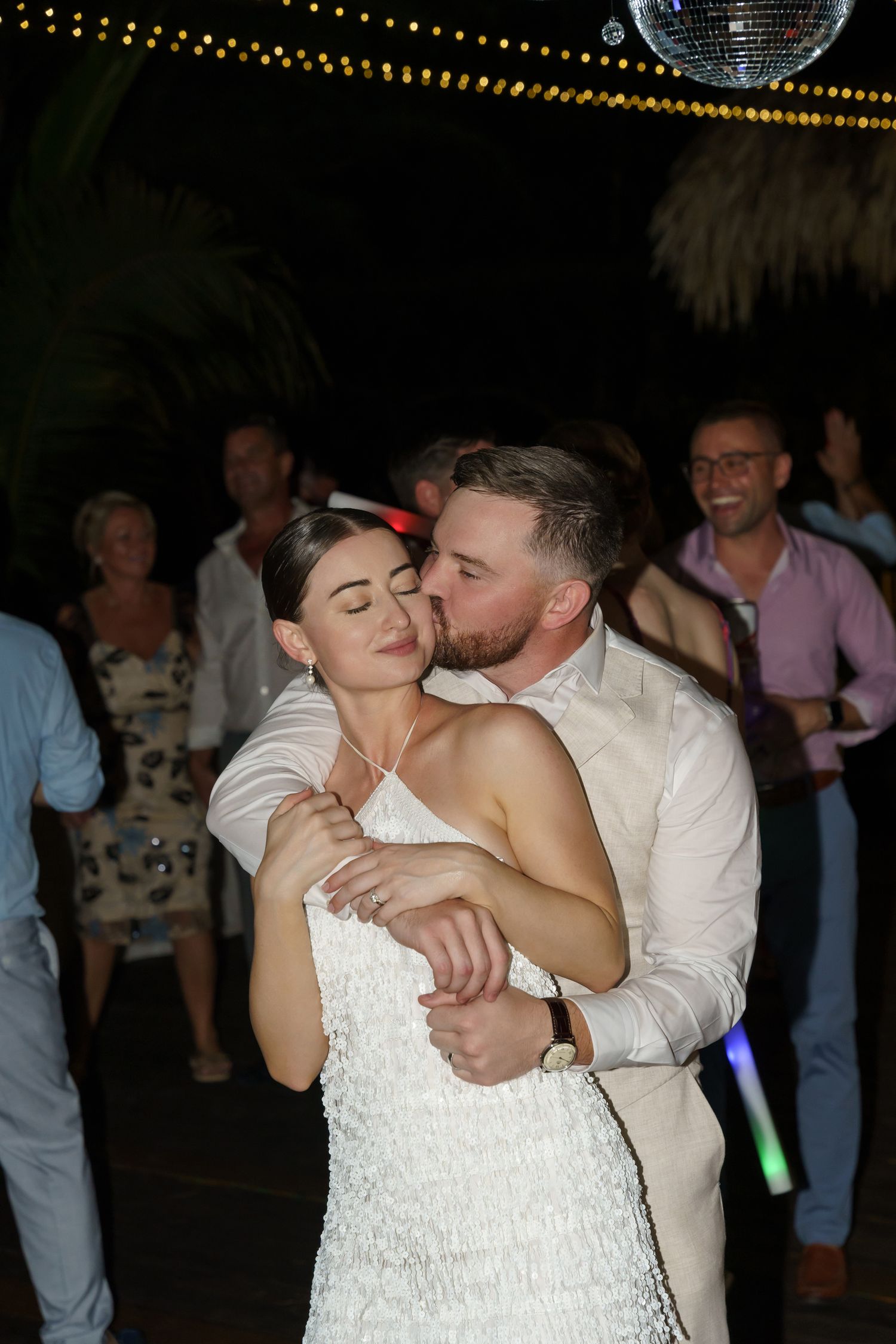 A bride and groom share an intimate dance together under a disco ball at their wedding reception.
