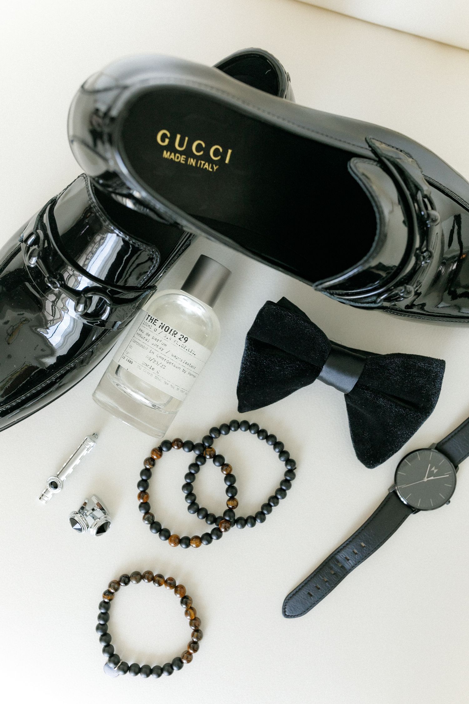Groom's accessories featuring Gucci patent shoes, bow tie, watch and beaded bracelets.