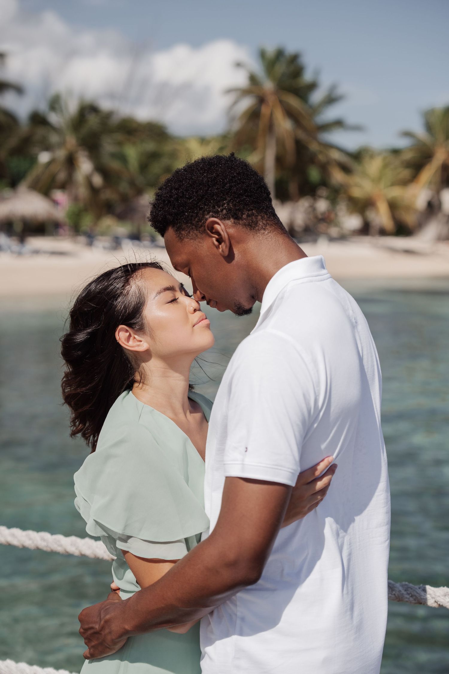 A tender moment between a couple against a tropical beach backdrop.
