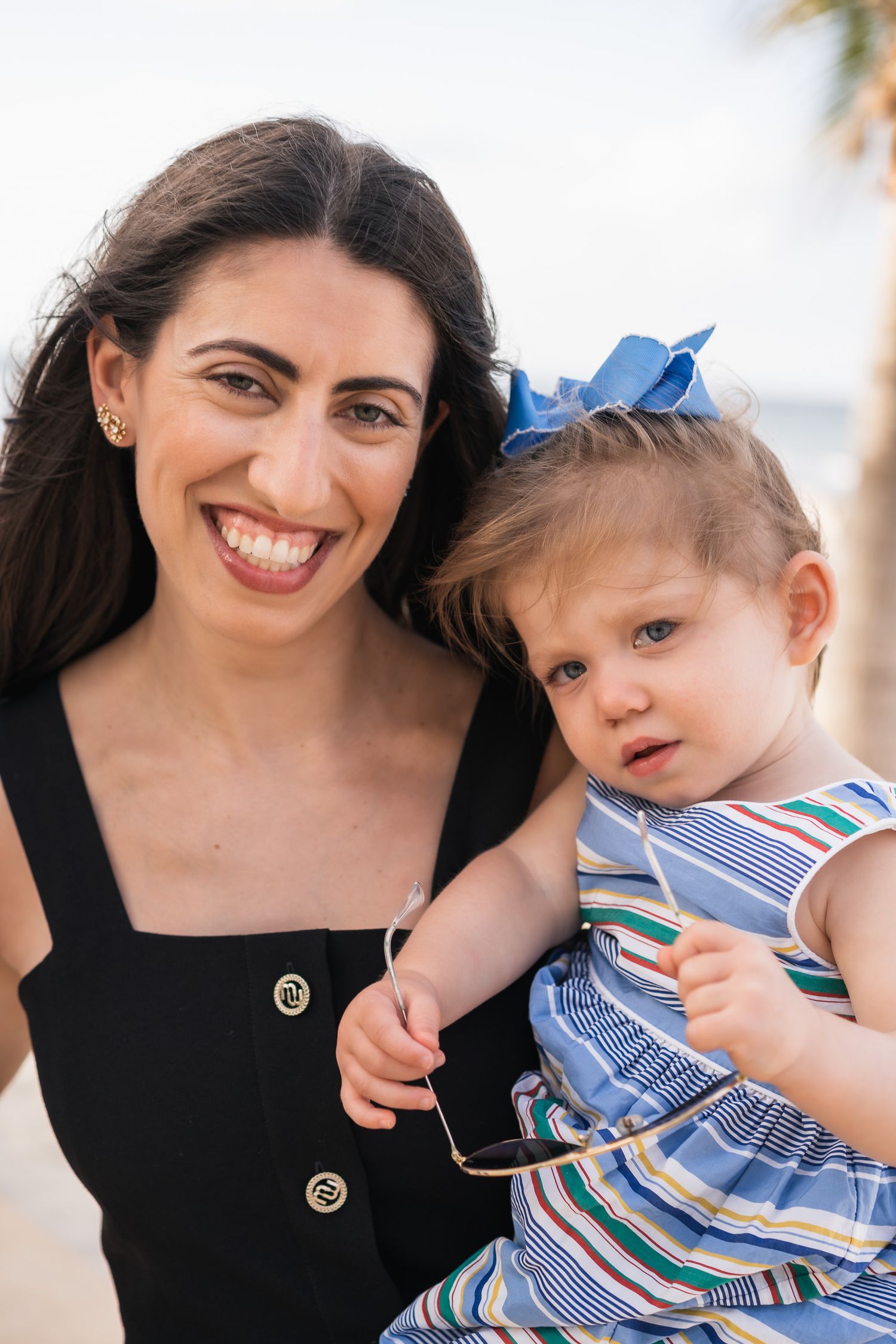Closeup portrait of parent and child in matching blue striped dress outdoors.
