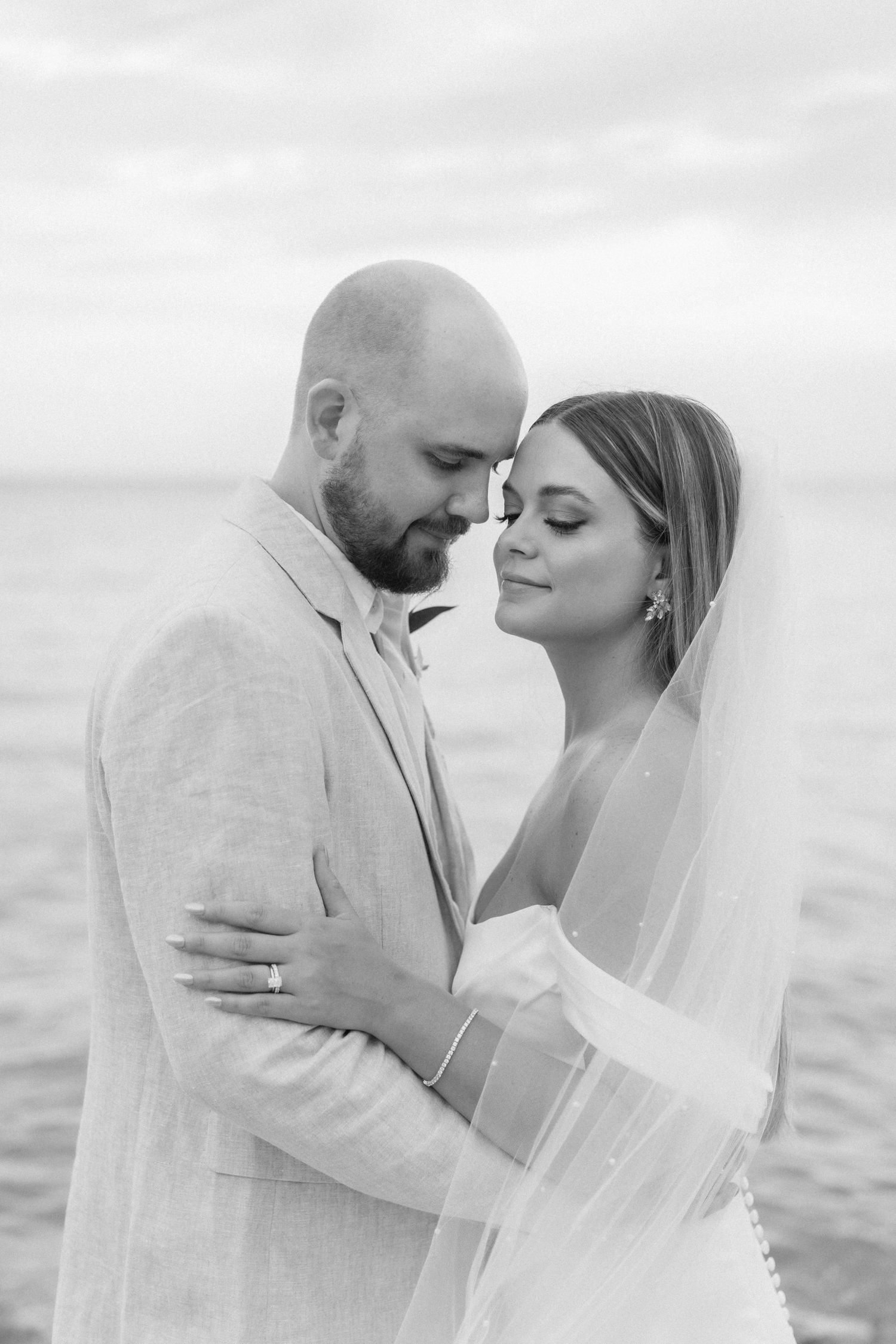 Intimate black and white portrait of newlyweds by the ocean.