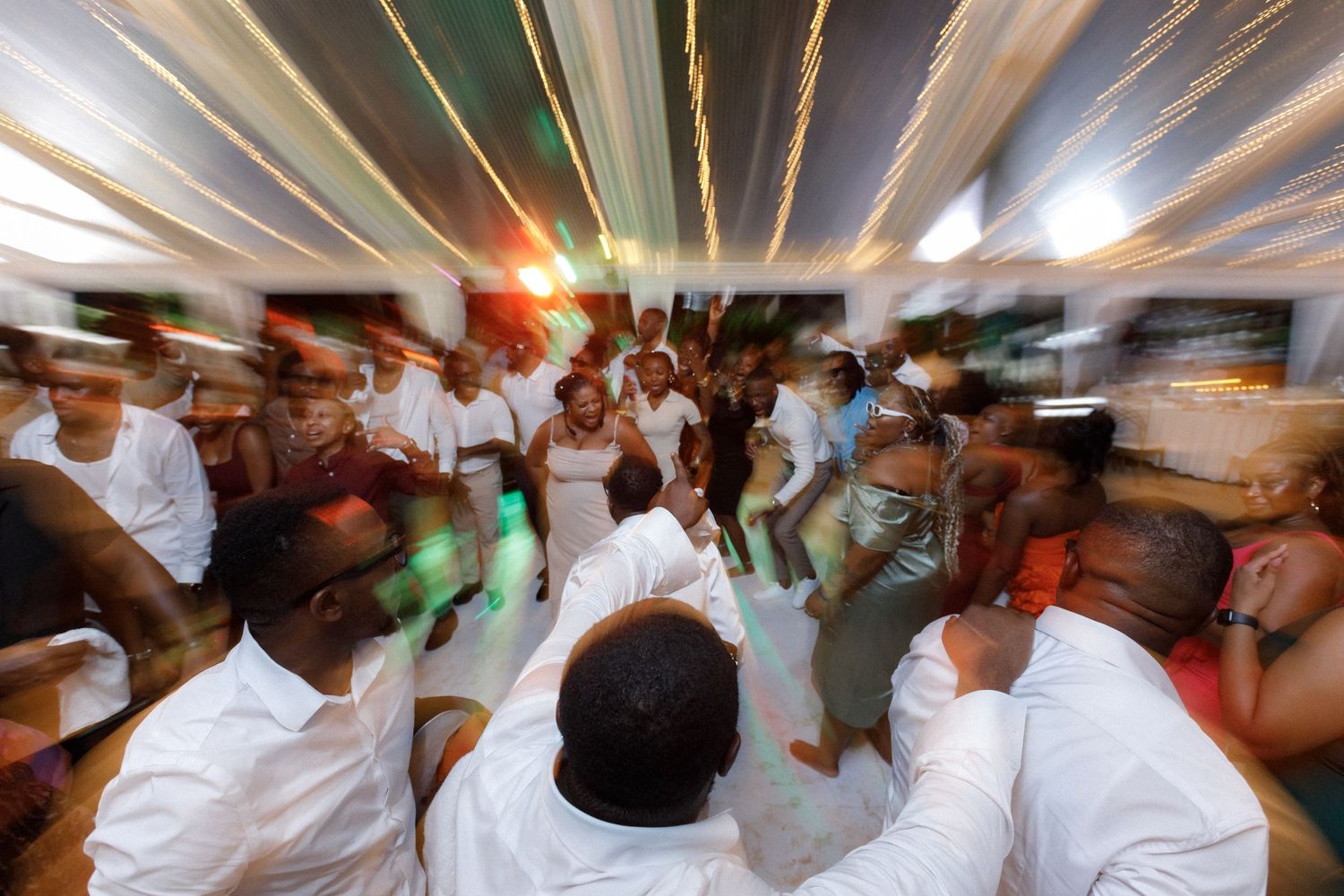 Dynamic motion-blur photograph captures the energy of wedding guests dancing in a circle.