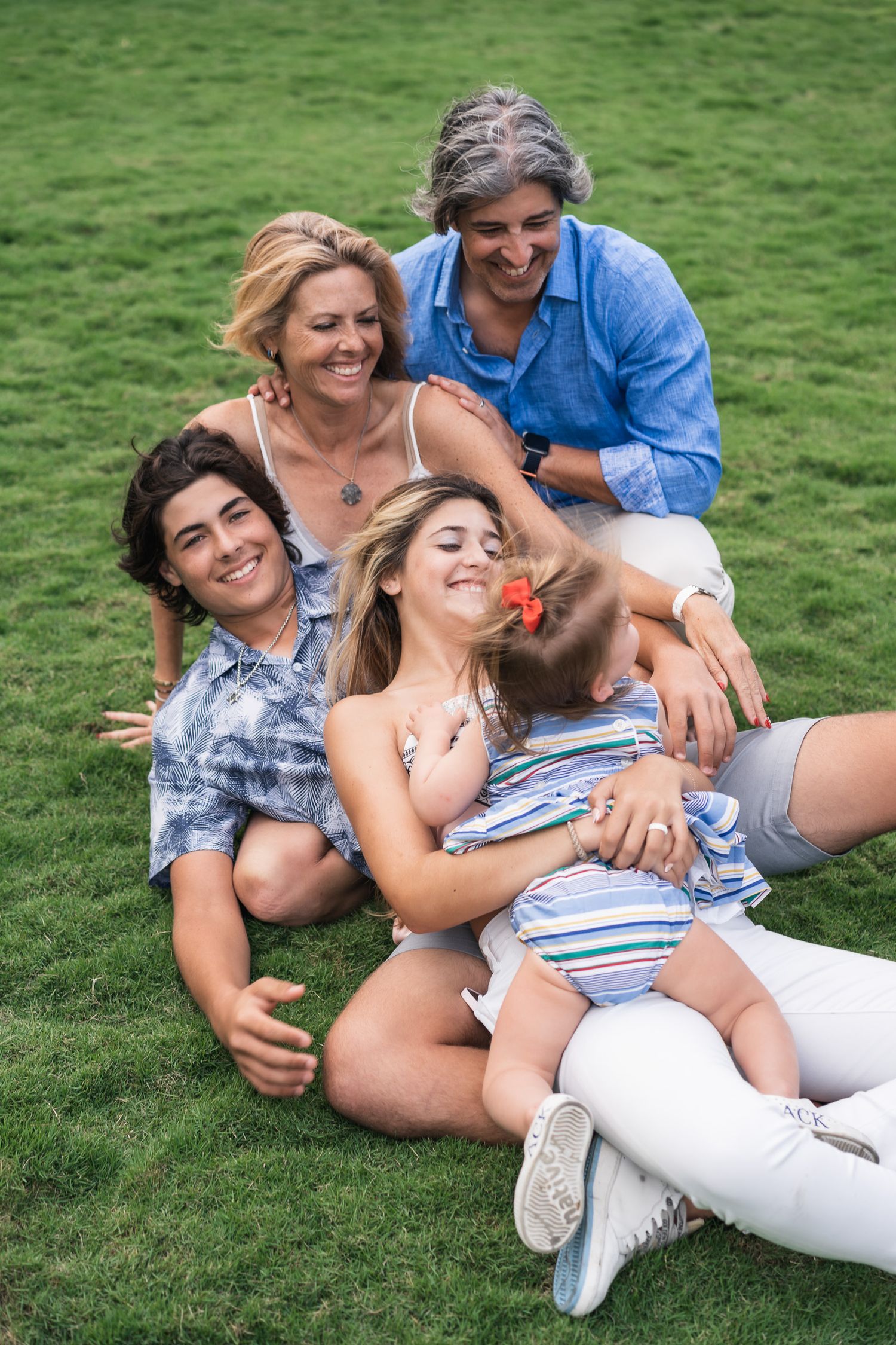 Family enjoying quality time together on a grassy lawn while relaxing and laughing.