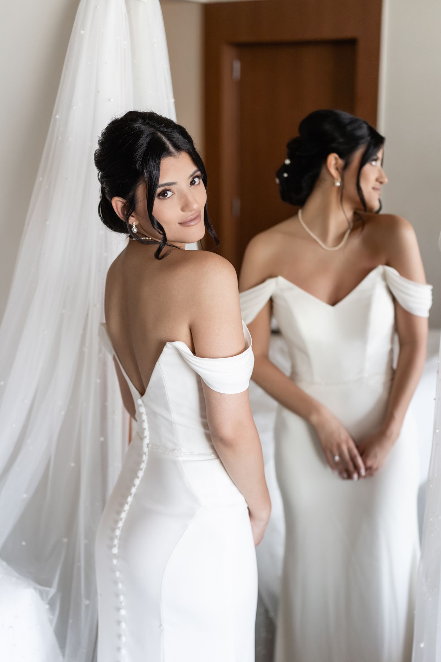 Elegant bridal portrait in fitted white wedding gown reflected in mirror.
