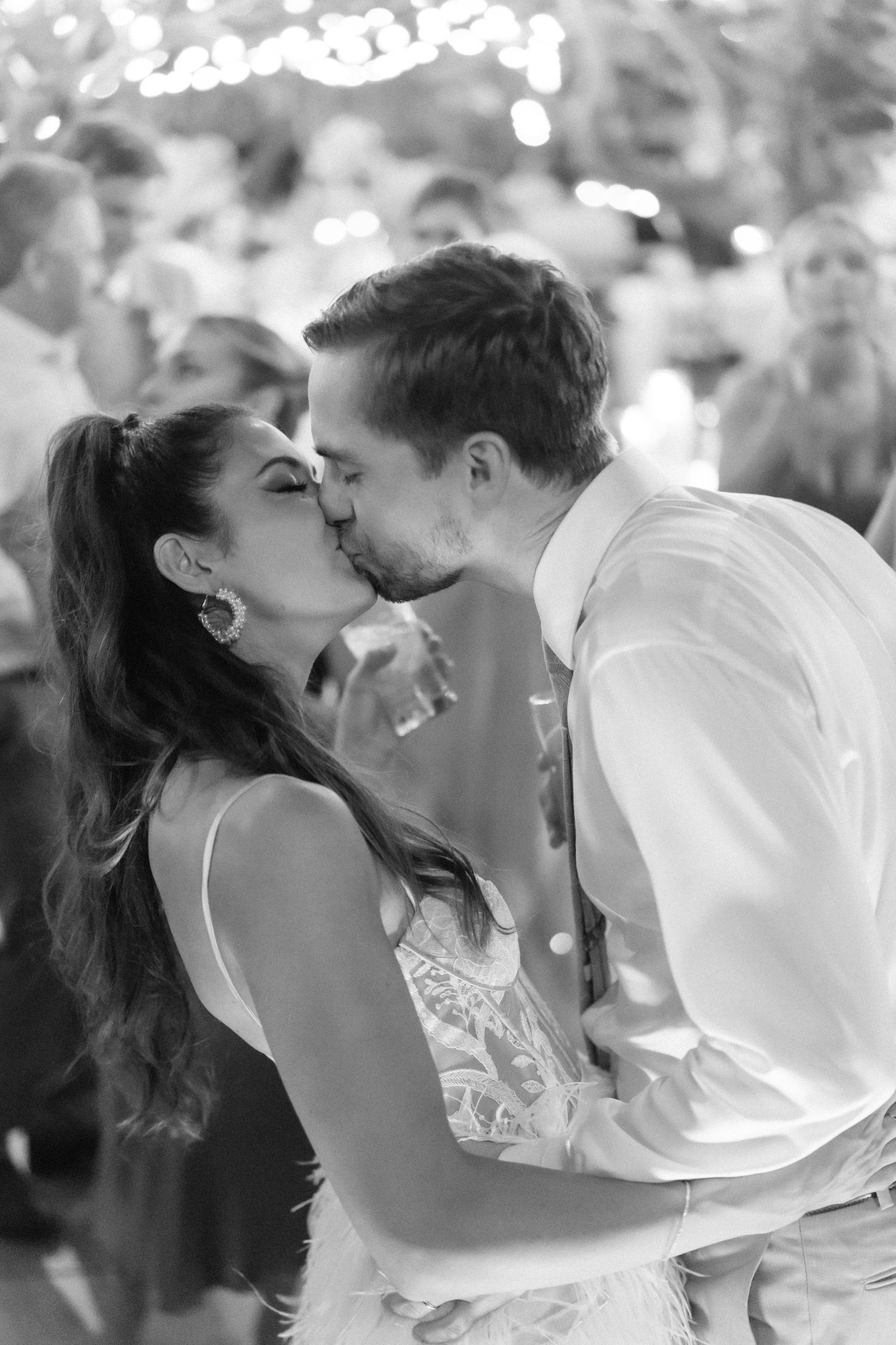 Romantic black and white portrait of newlyweds sharing kiss at reception.