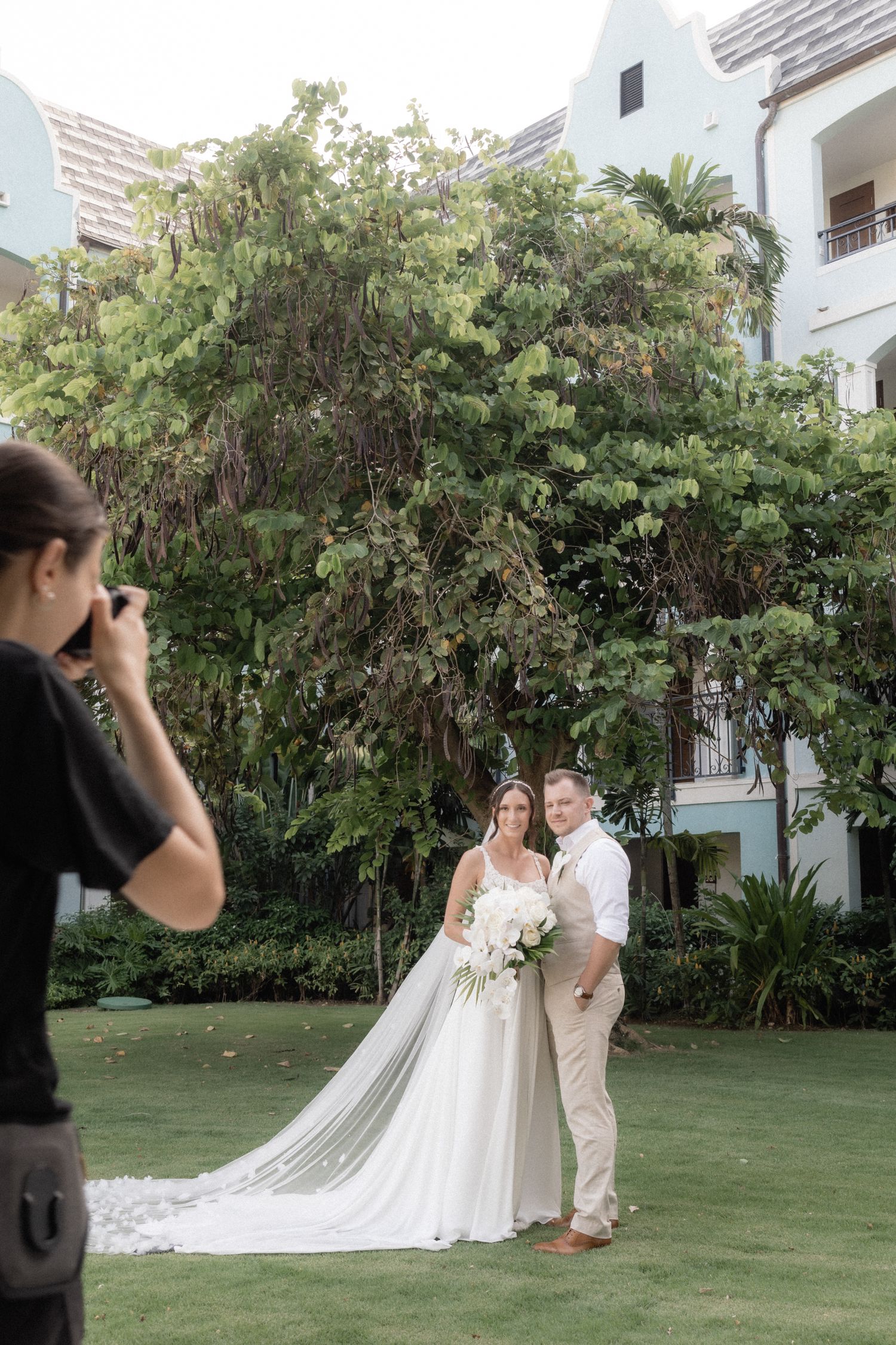 Wedding photographer captures romantic outdoor portraits of a couple in a lush garden setting at a tropical venue.