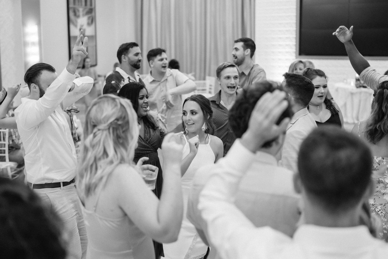 Wedding reception guests dancing and celebrating in black and white photography.
