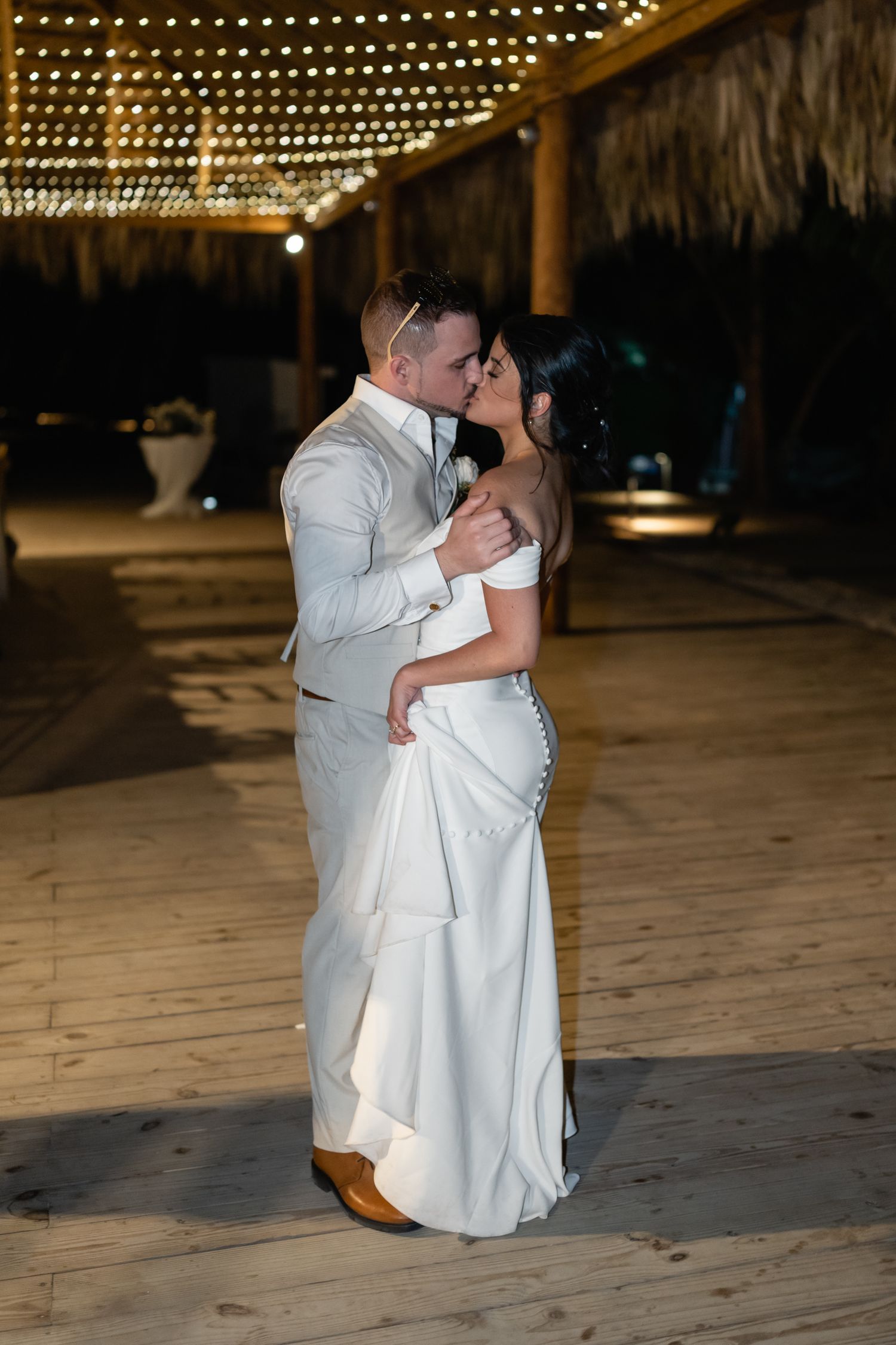 Romantic first dance moment under string lights at an outdoor wedding reception.