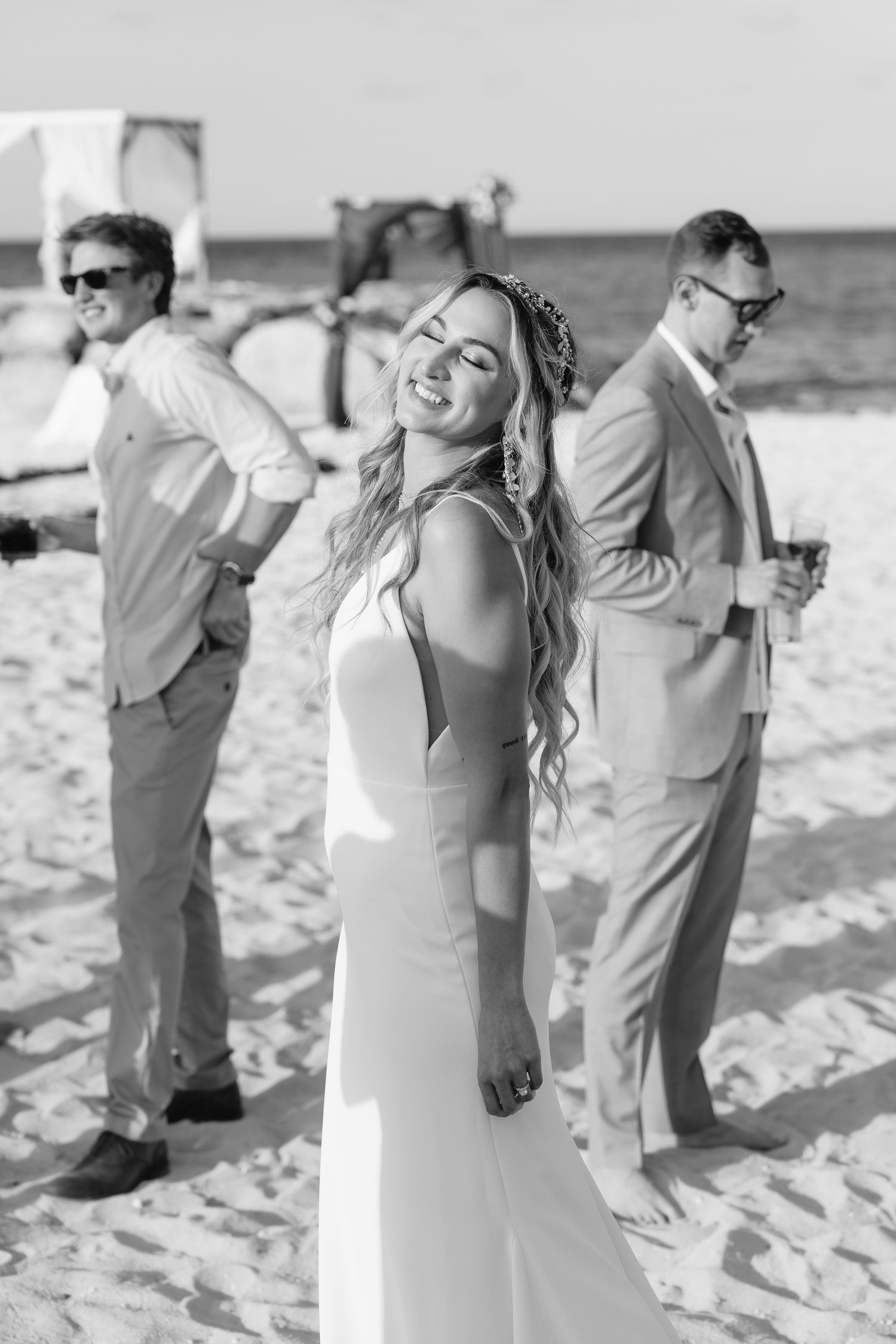 Black and white beach wedding portrait with attendants in light colored attire.