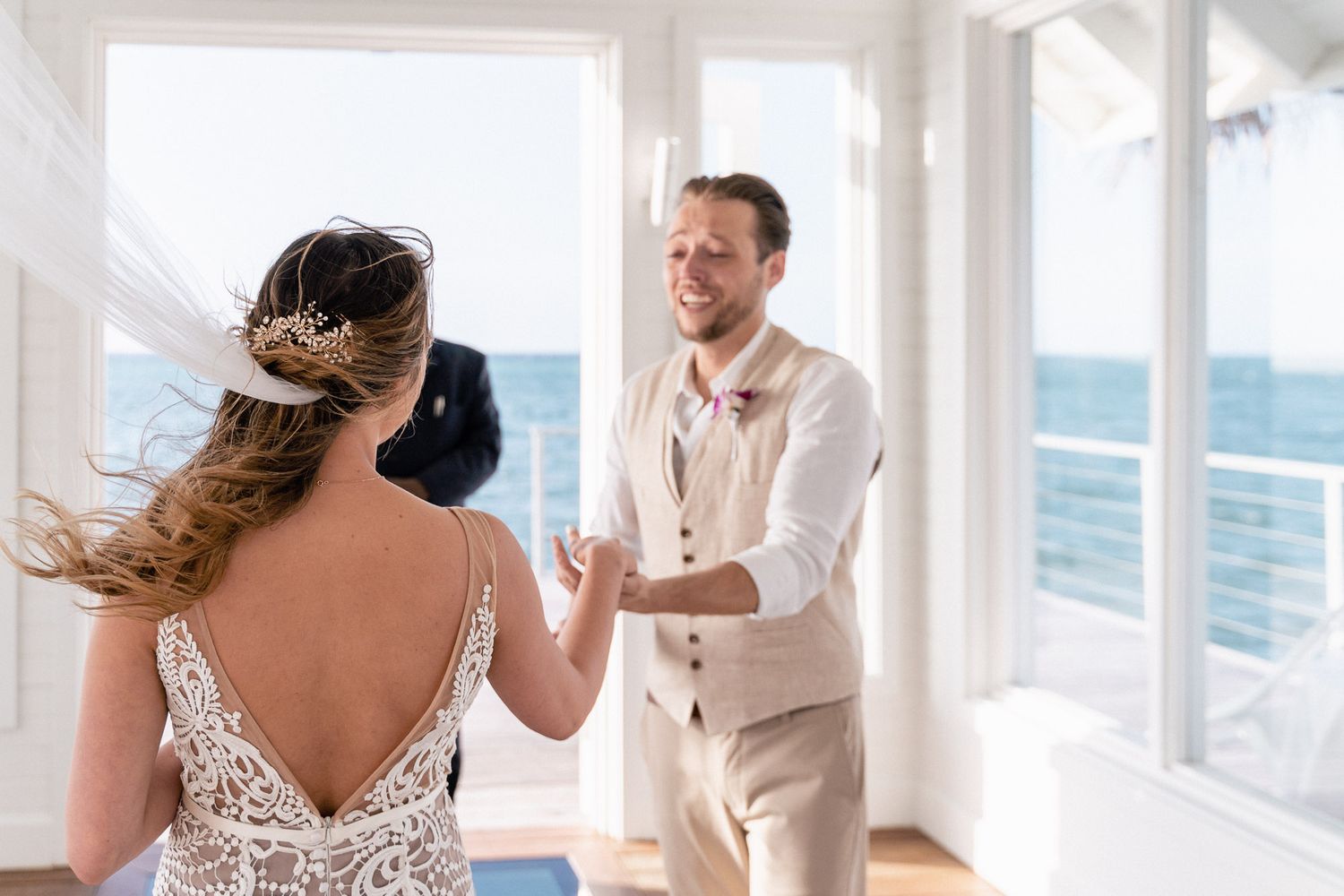 A romantic first look moment between newlyweds in a bright oceanfront venue.