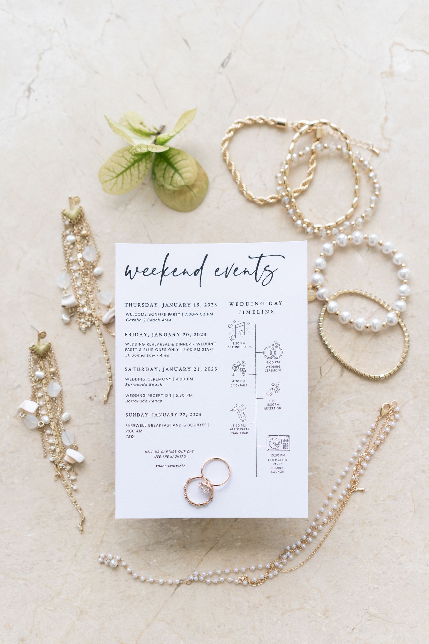 Wedding weekend itinerary card styled with jewelry and floral elements on white surface.