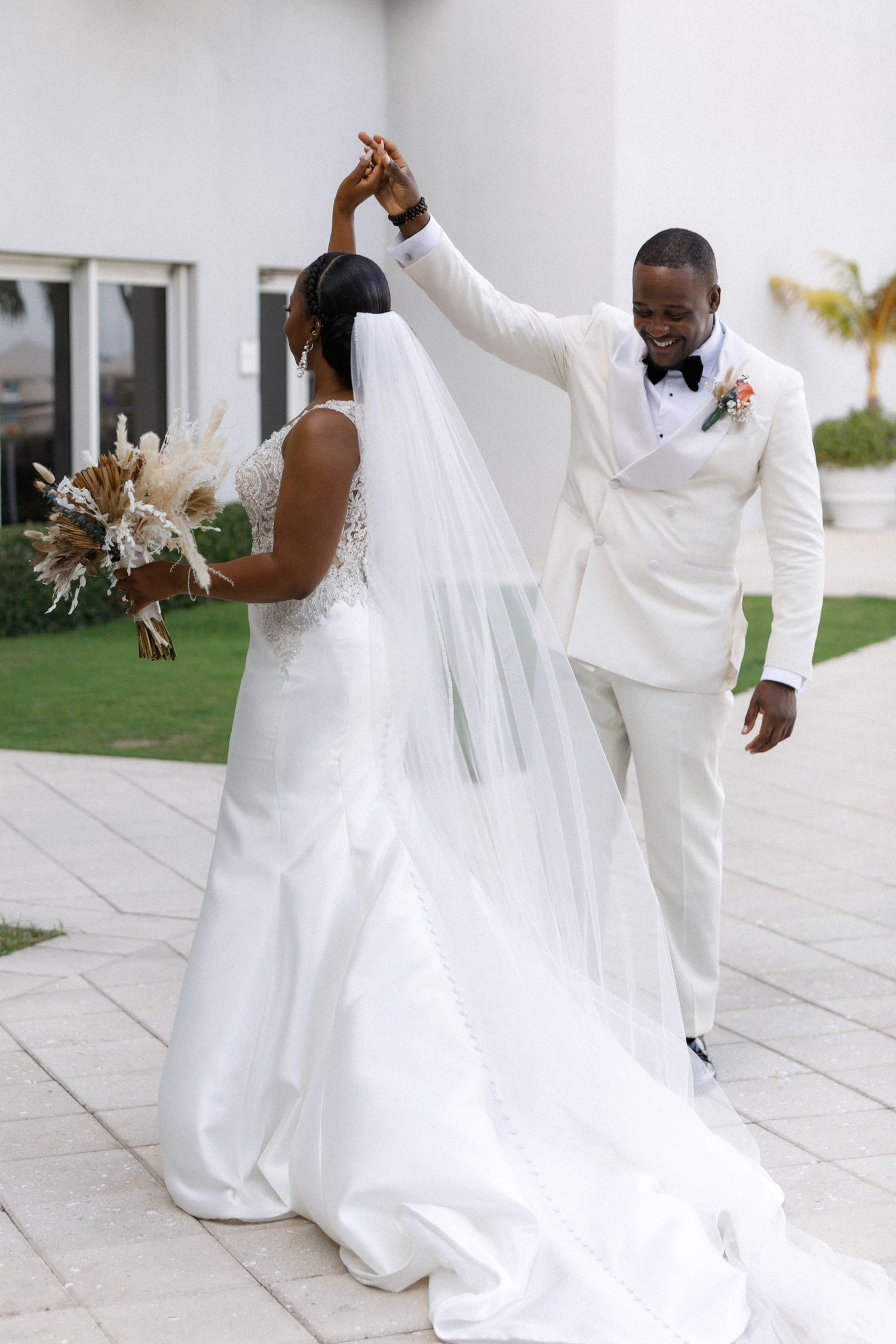A couple shares a romantic dance moment at their wedding, with the bride in a flowing white gown and groom in crisp white suit.