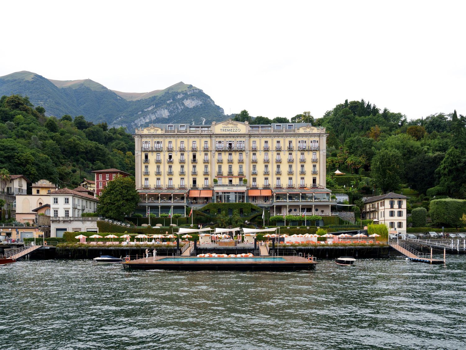 A scenic panoramic view of Lake Como waterfront in Italy with historic buildings and boats along the shoreline.