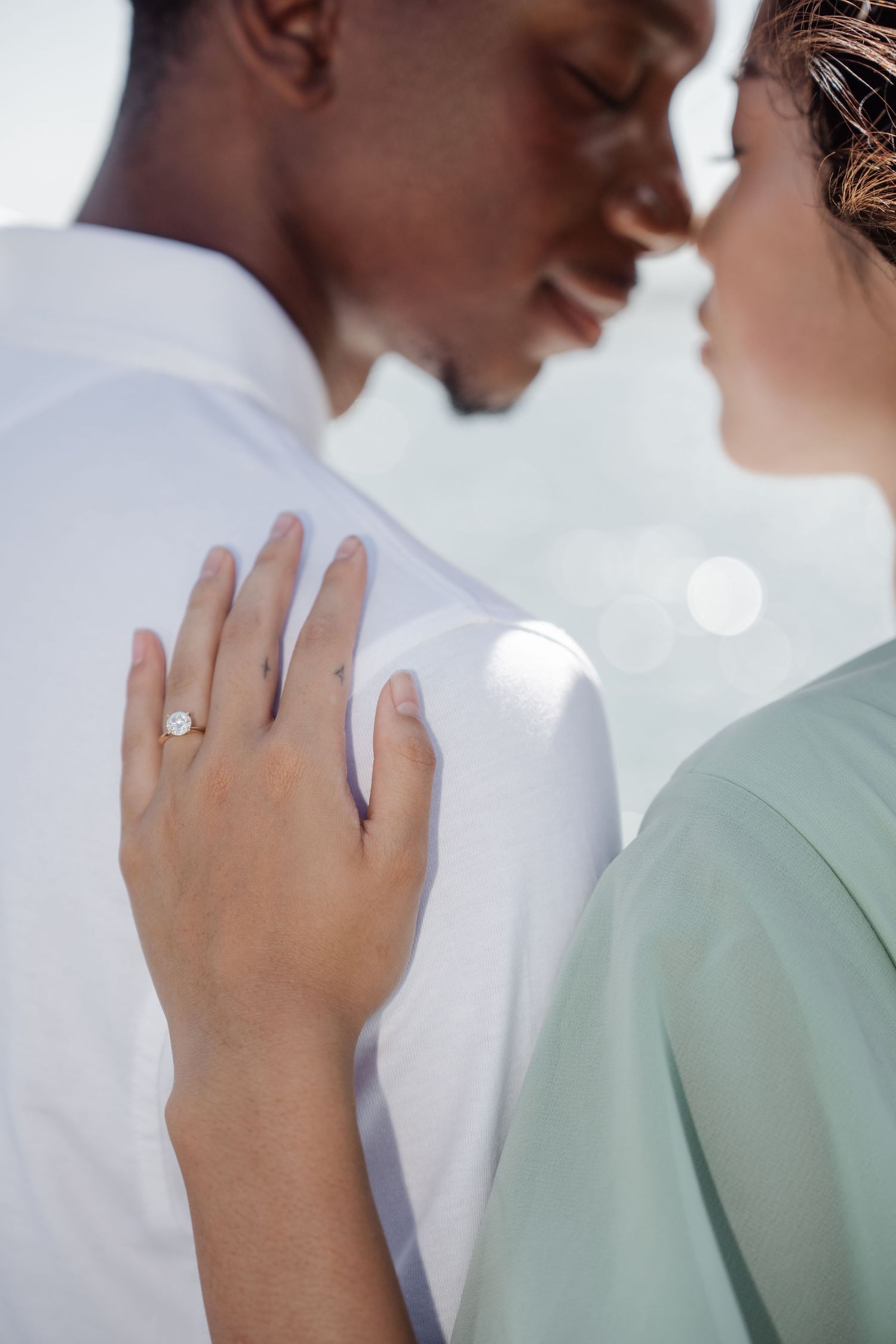 Close-up of an intimate moment showing an engagement ring on a hand.