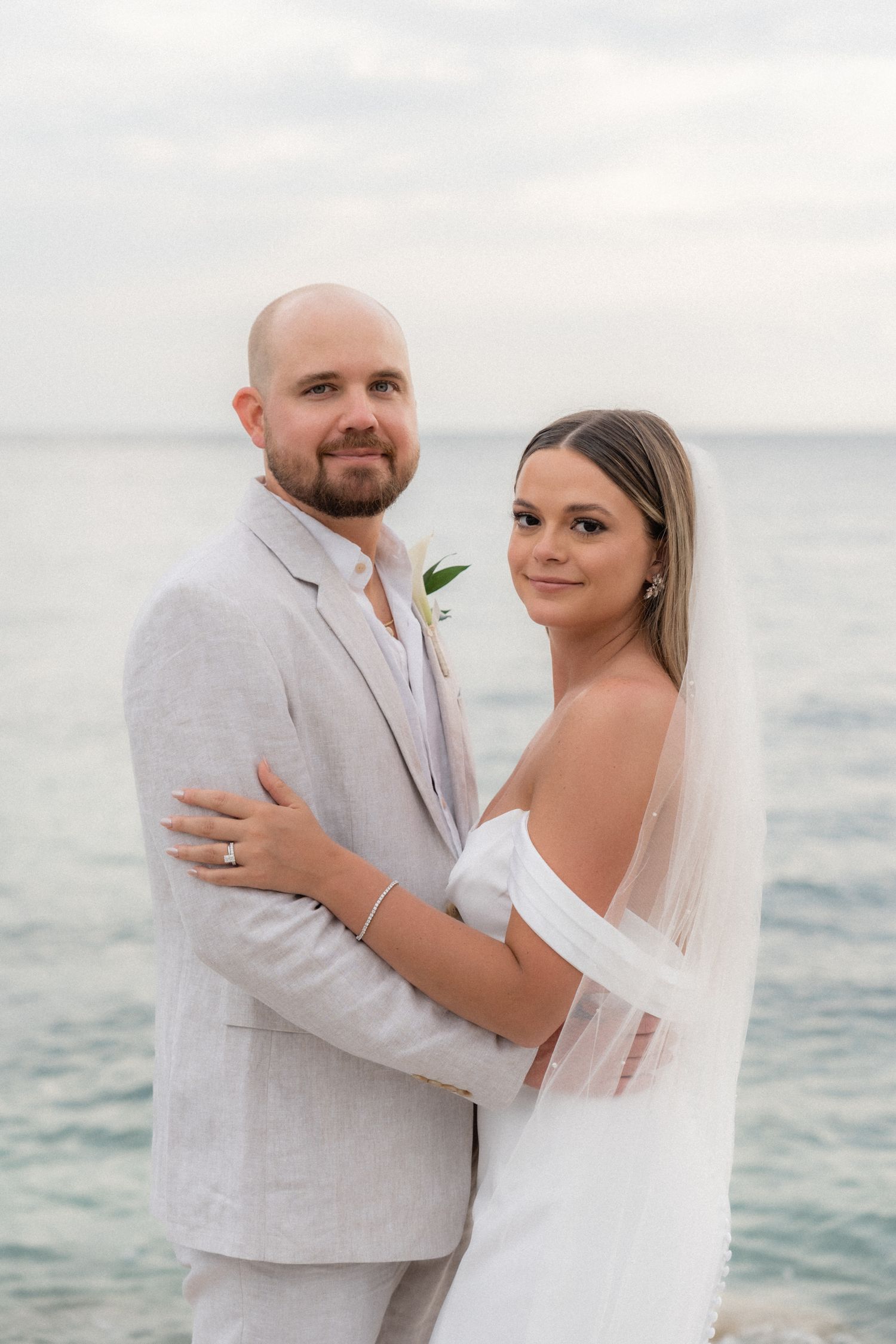 Romantic beachside wedding portrait with ocean waves in the background.