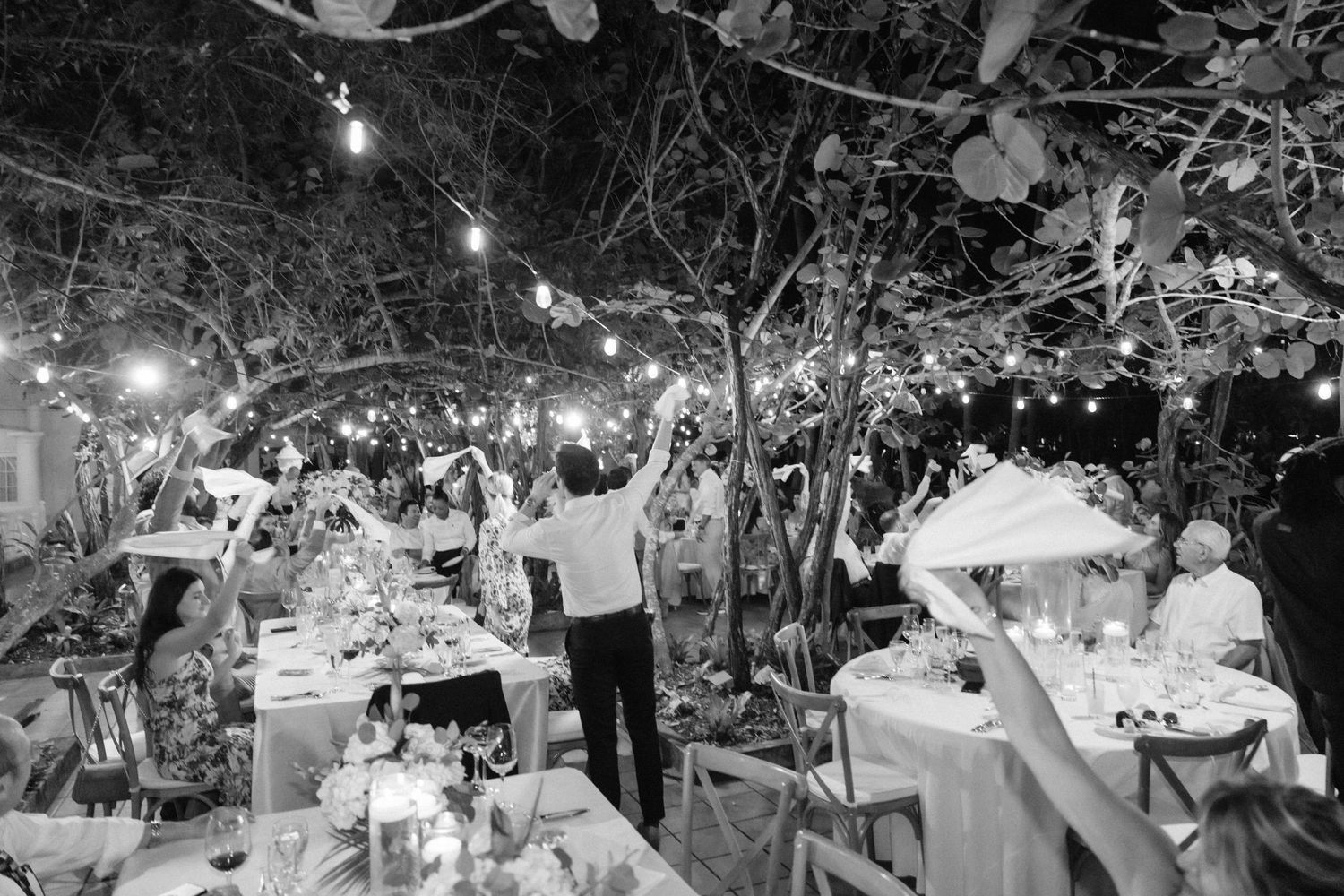An outdoor wedding reception venue decorated with string lights and elegant table settings.