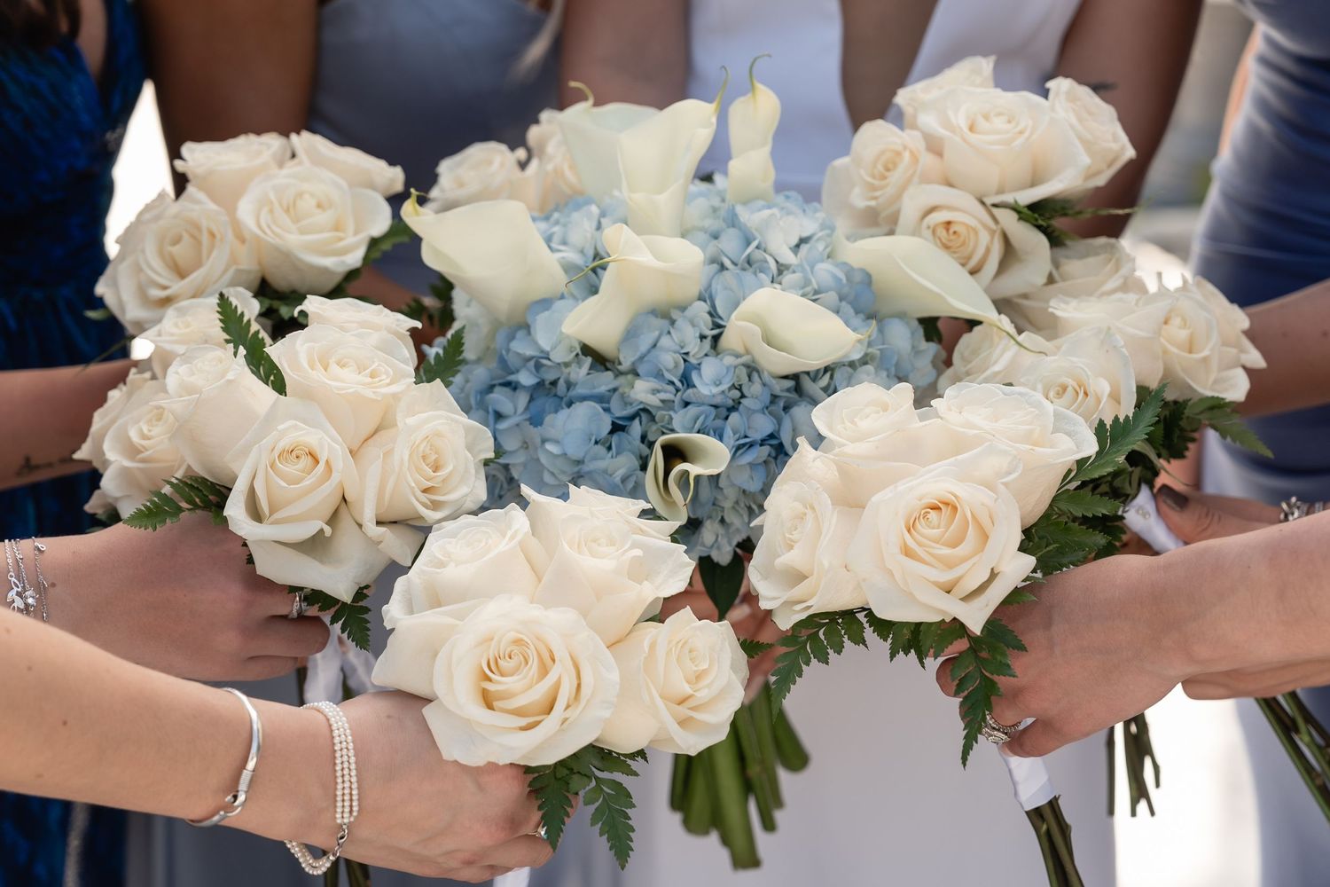 Wedding bouquets featuring white roses and blue hydrangeas held together.