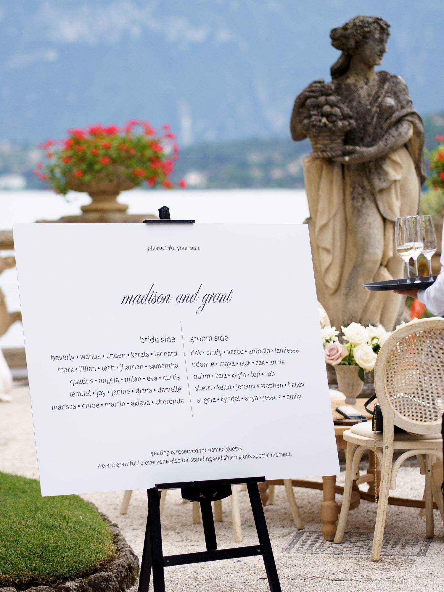 Elegant outdoor wedding ceremony setup with white chairs and signage against a scenic mountain backdrop.