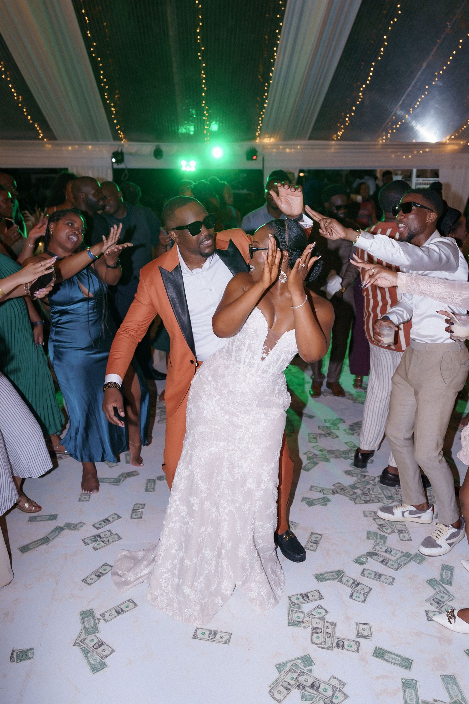 Lively wedding reception dance floor with money shower and green lighting effects.
