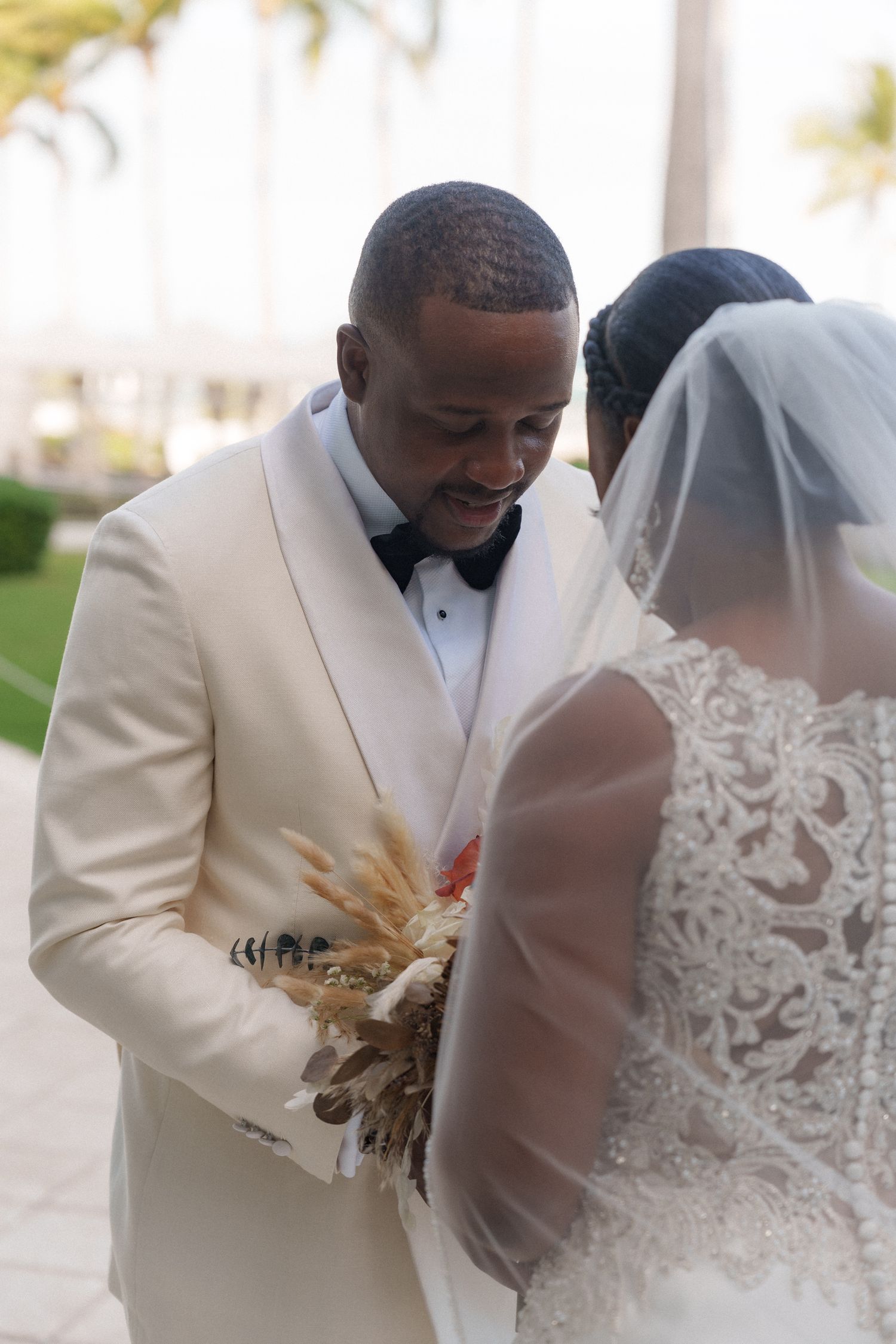 A groom in white tuxedo sharing an intimate moment during the outdoor wedding ceremony.
