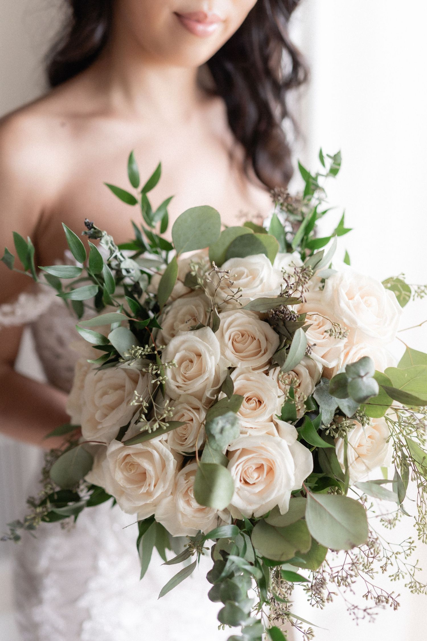 A delicate bridal bouquet featuring cream roses and eucalyptus greenery.