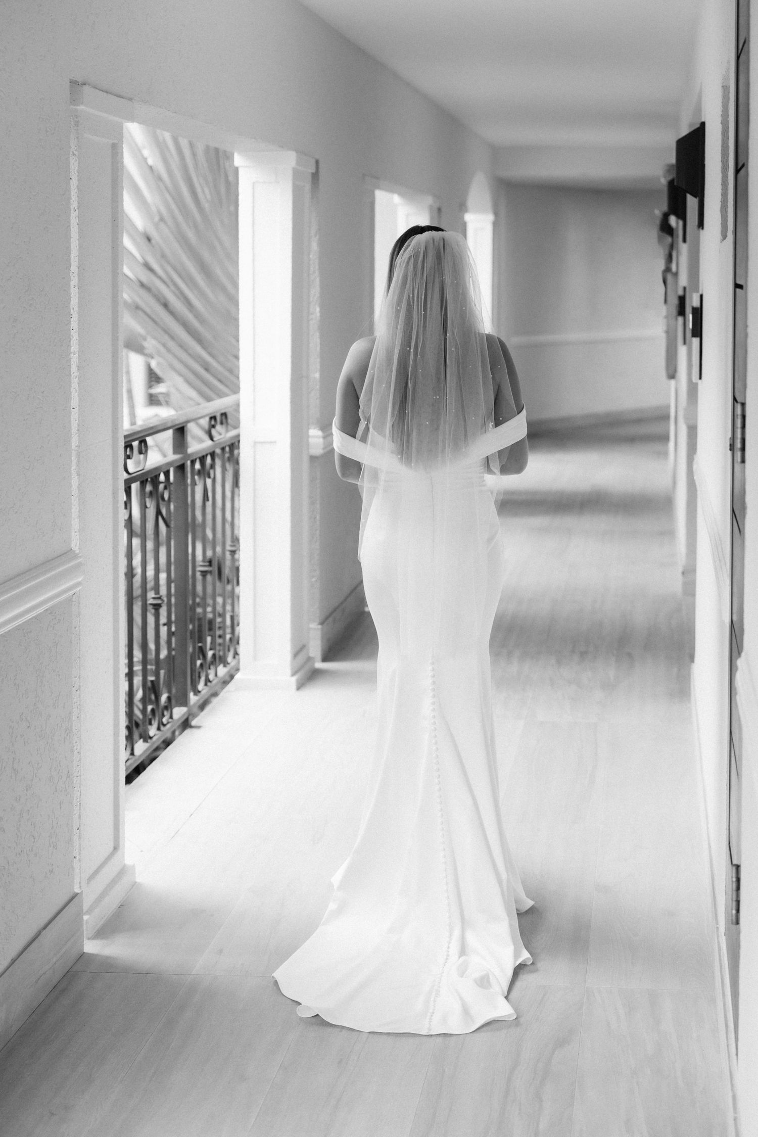 Elegant bridal gown silhouette in black and white hallway photograph.