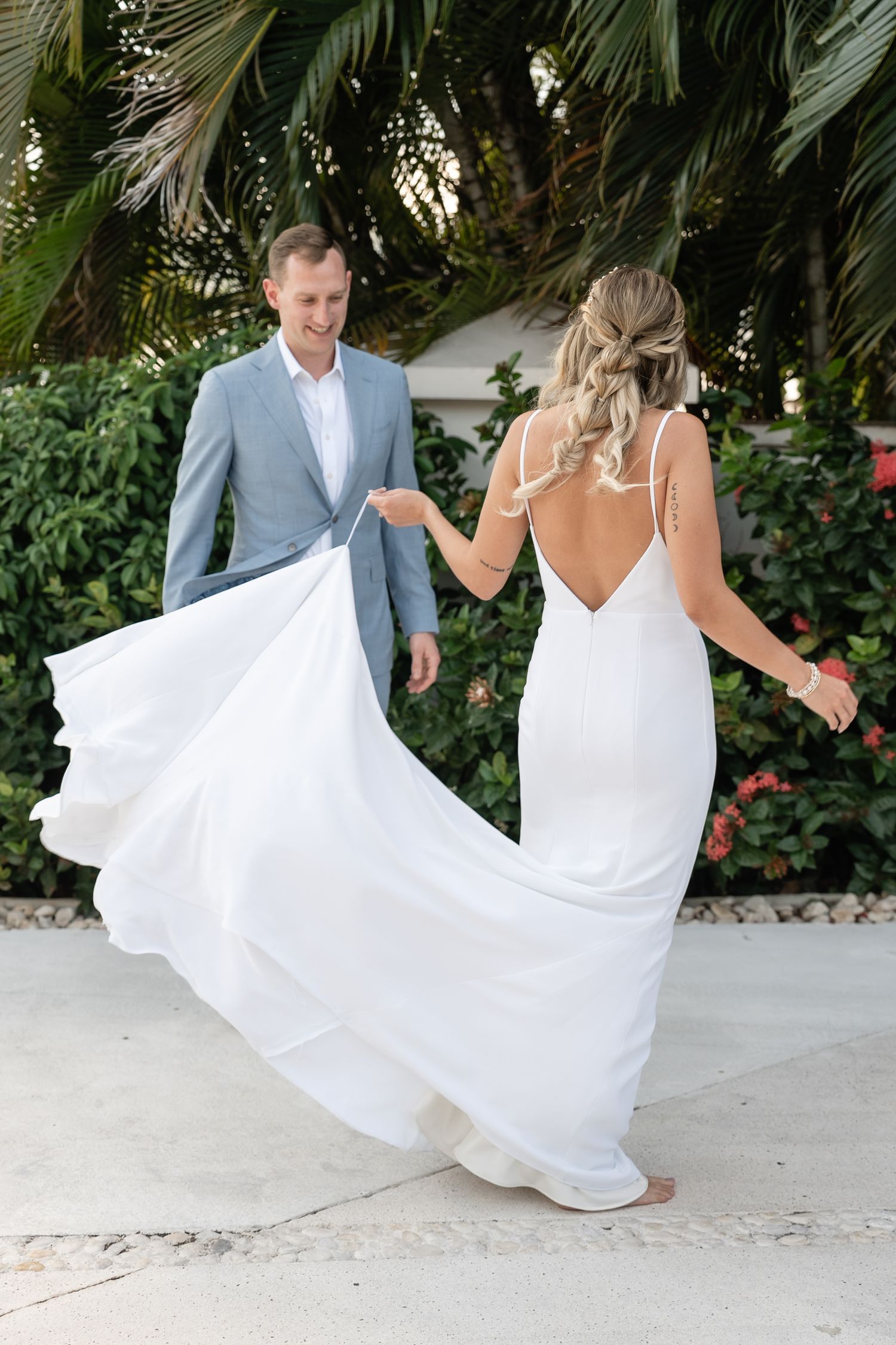 A flowing white wedding dress twirls against a tropical garden backdrop.