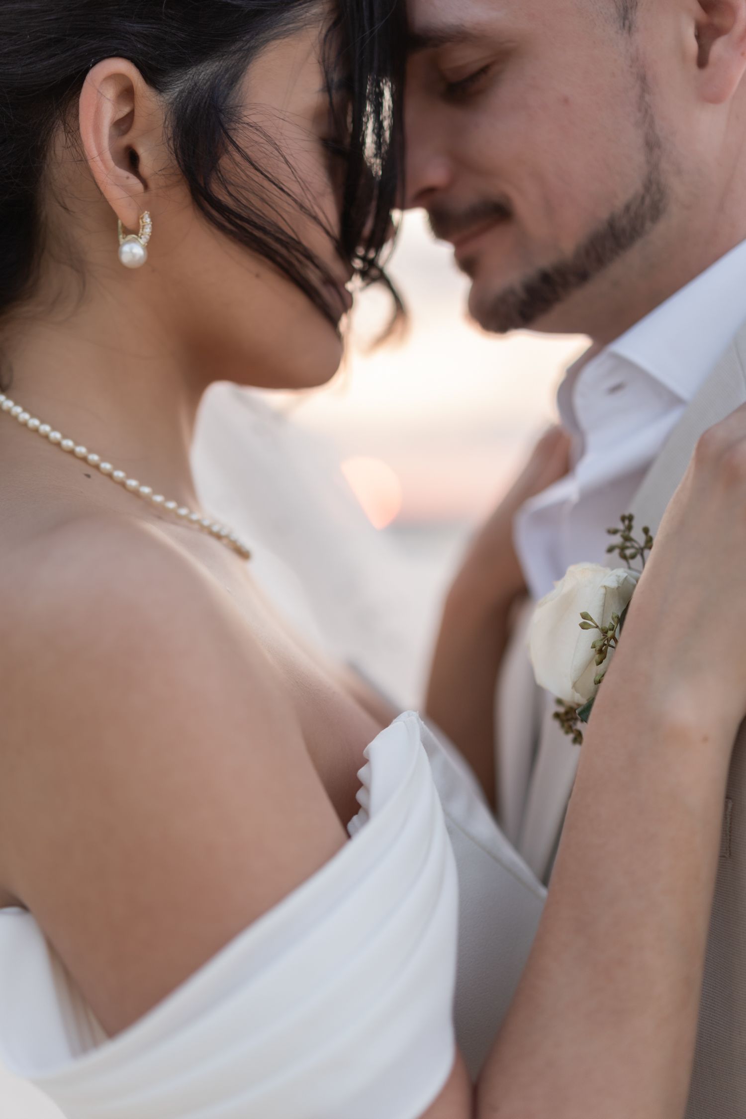 A tender close-up moment between a couple in formal wedding attire.