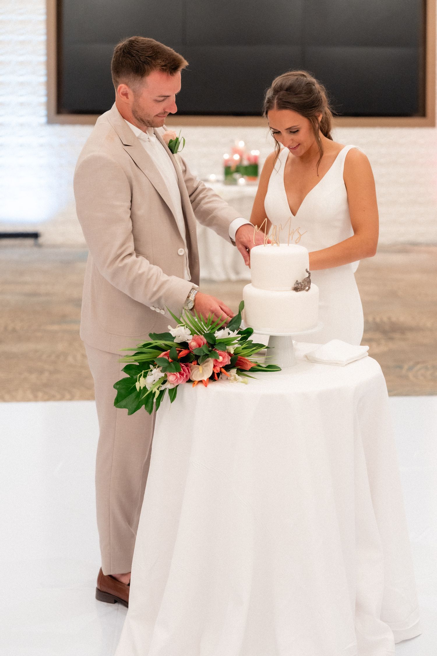 Newlyweds cut their wedding cake together during reception celebration.