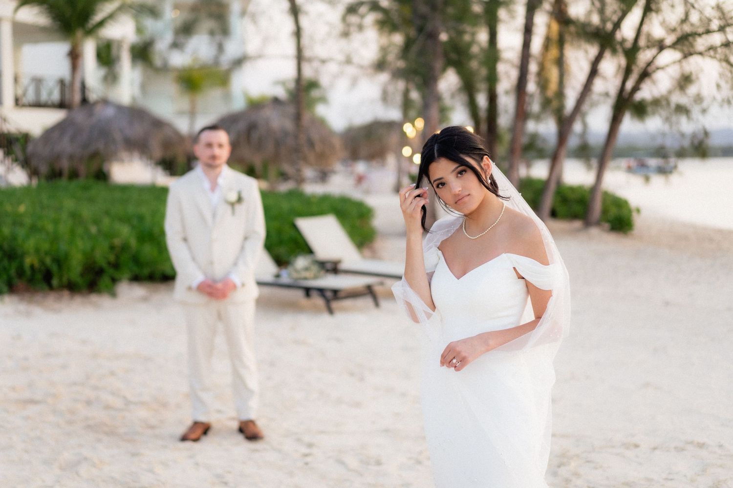 Emotional moment during beach wedding with ocean and palm trees in background.