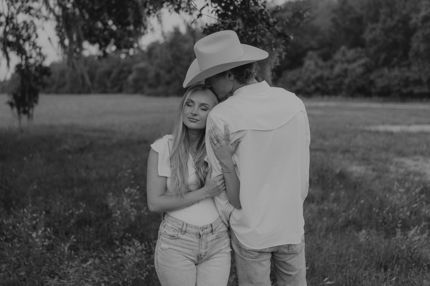 Black and white photo of a romantic couple sharing an intimate moment in a meadow on a summer afternoon.