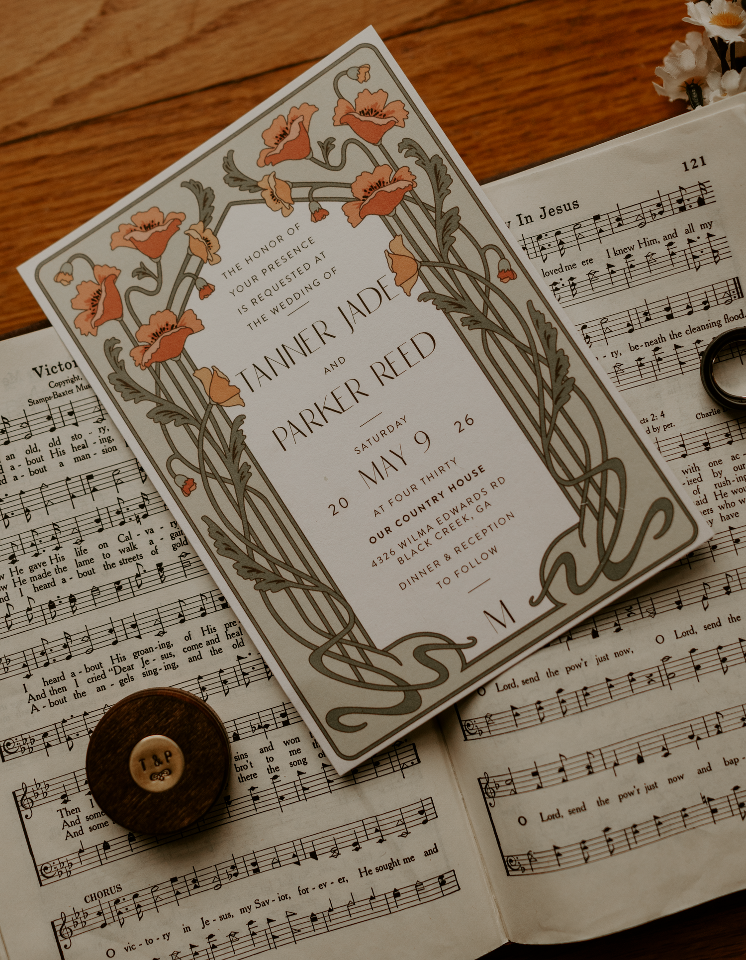 Art nouveau wedding invitation for Tahler Jade and Parker Reed, May 9, displayed on open sheet music.
