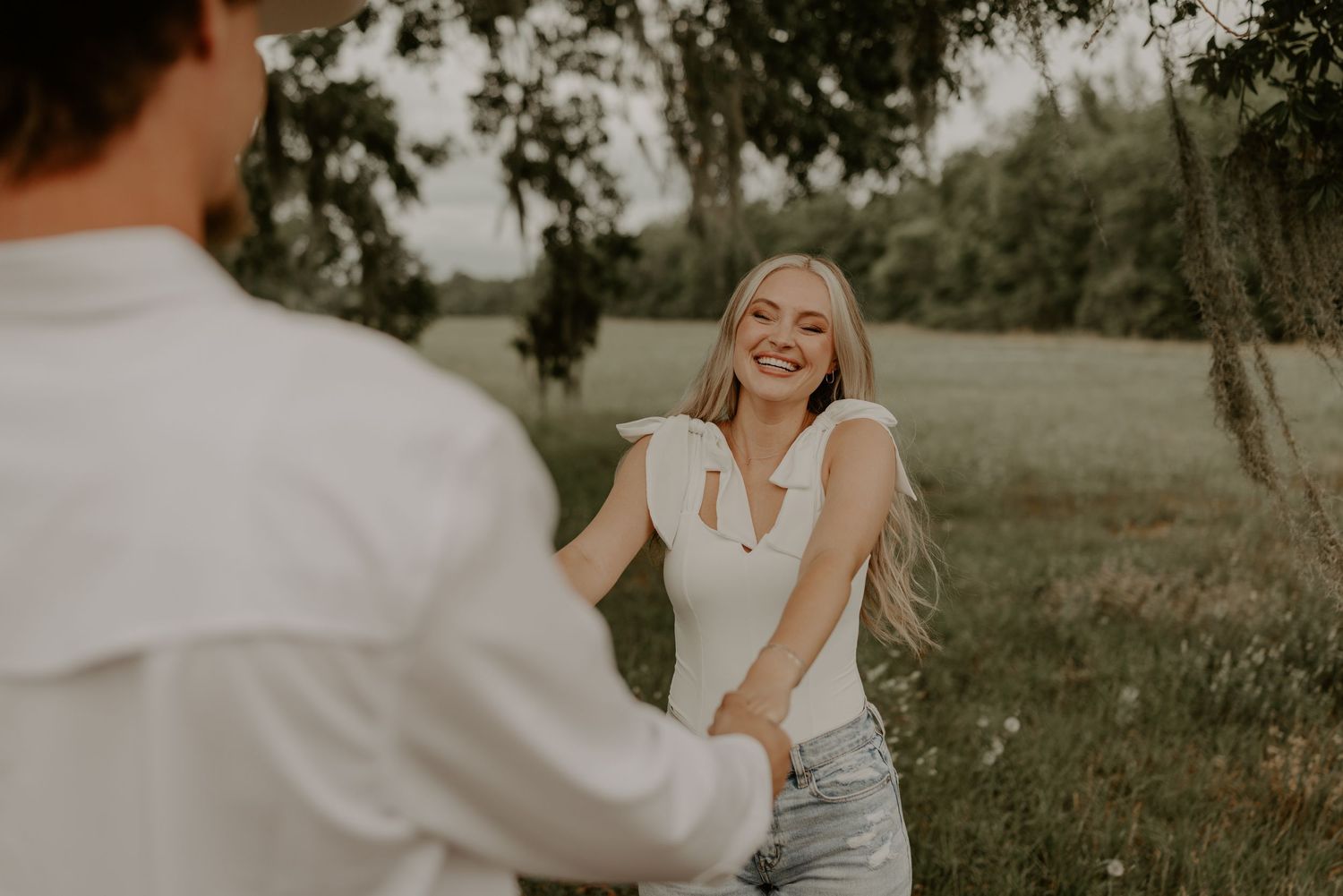 A couple shares a joyful moment together in a dreamy outdoor setting during a sunny summer photoshoot.