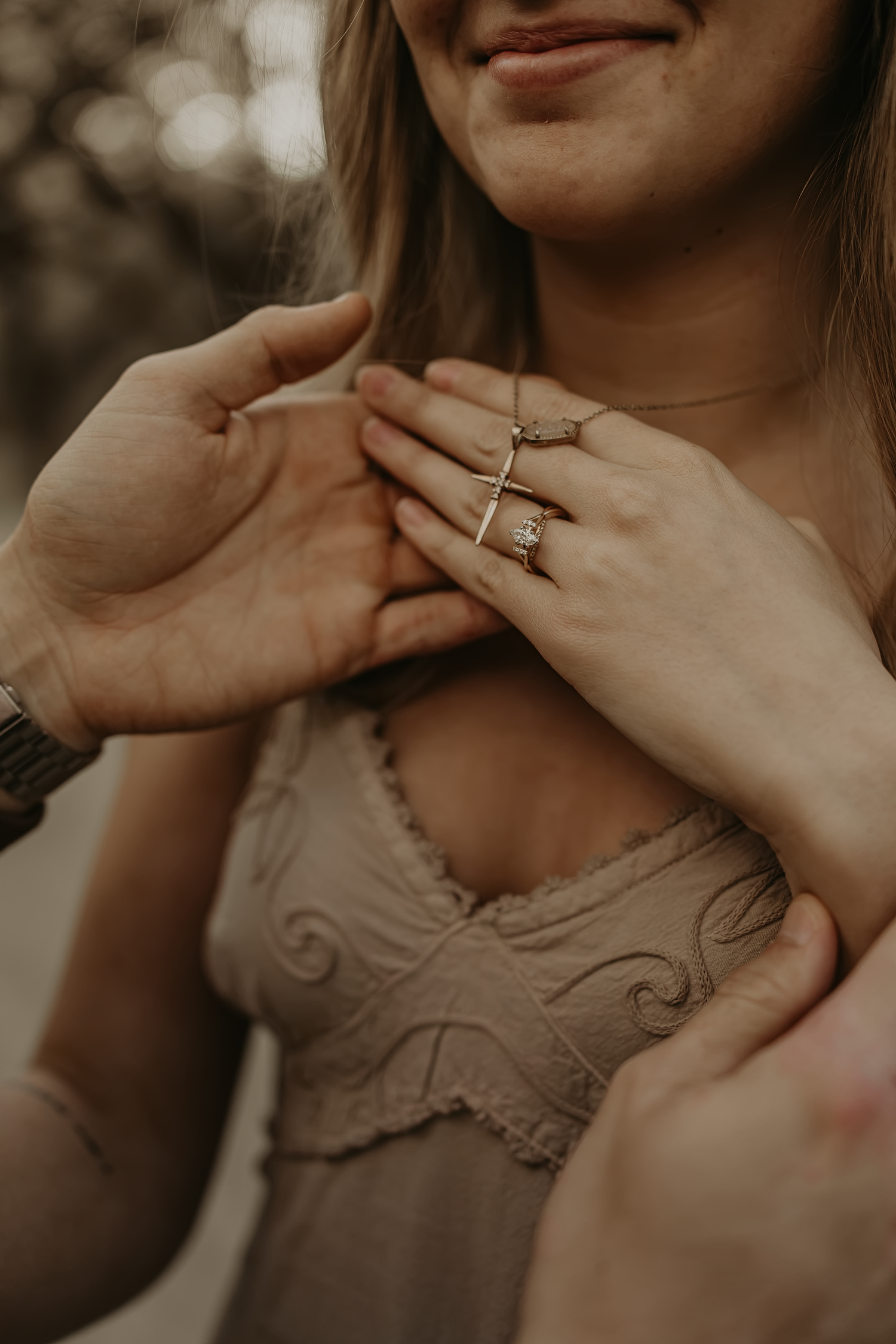 Close up of hands displaying engagement ring with delicate lace details.