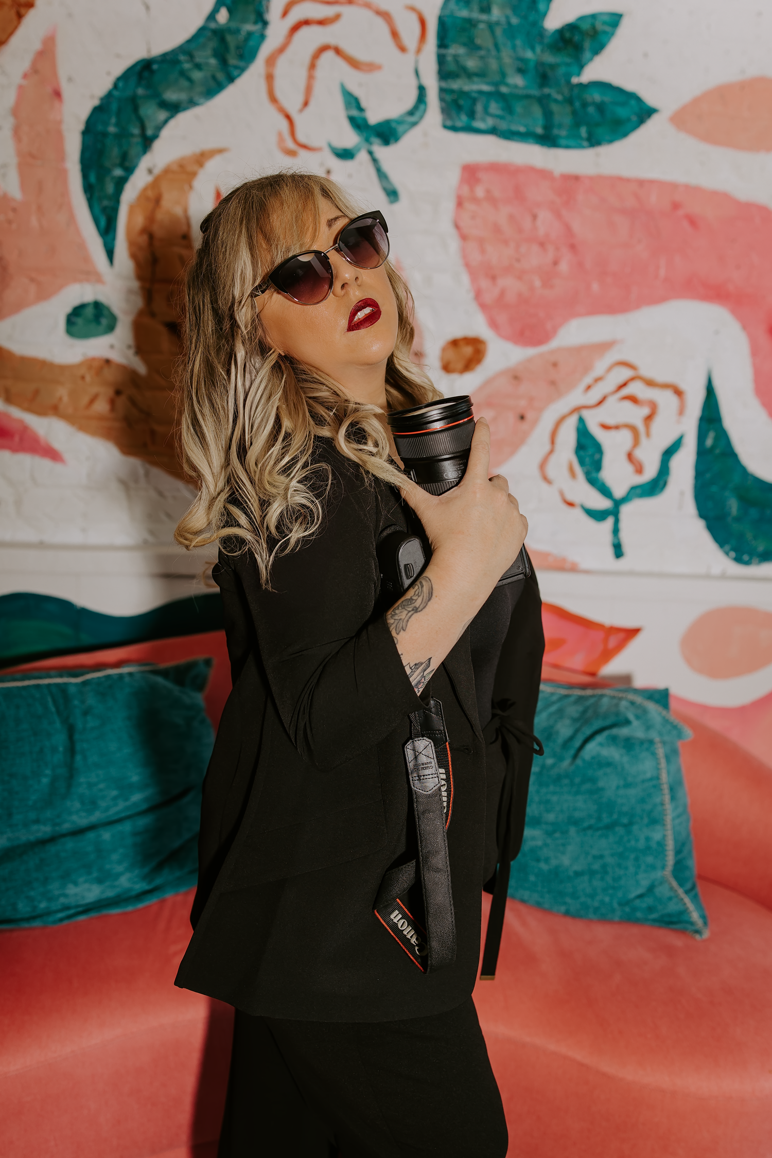Stylish woman in black outfit posing against colorful floral mural wall.

Georgia-based wedding and elopement photographer traveling through