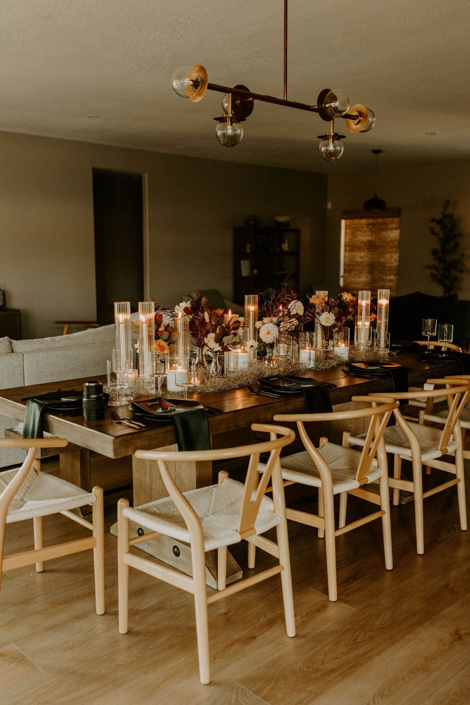 Elegant dining table setup with glass candle holders and wooden chairs for wedding reception.