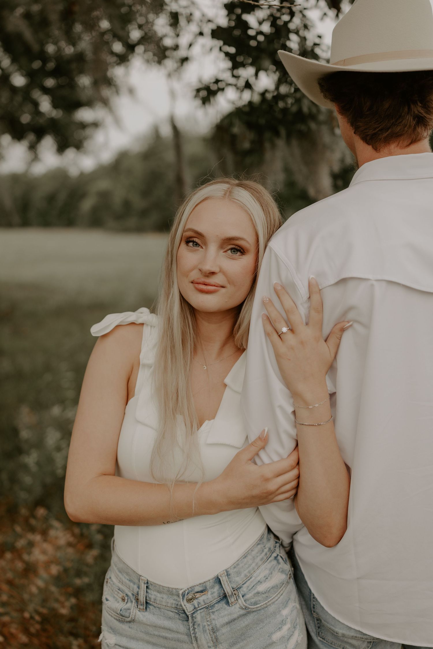 Romantic outdoor engagement photo sequence showing couple in casual white and denim outfits in natural surroundings.