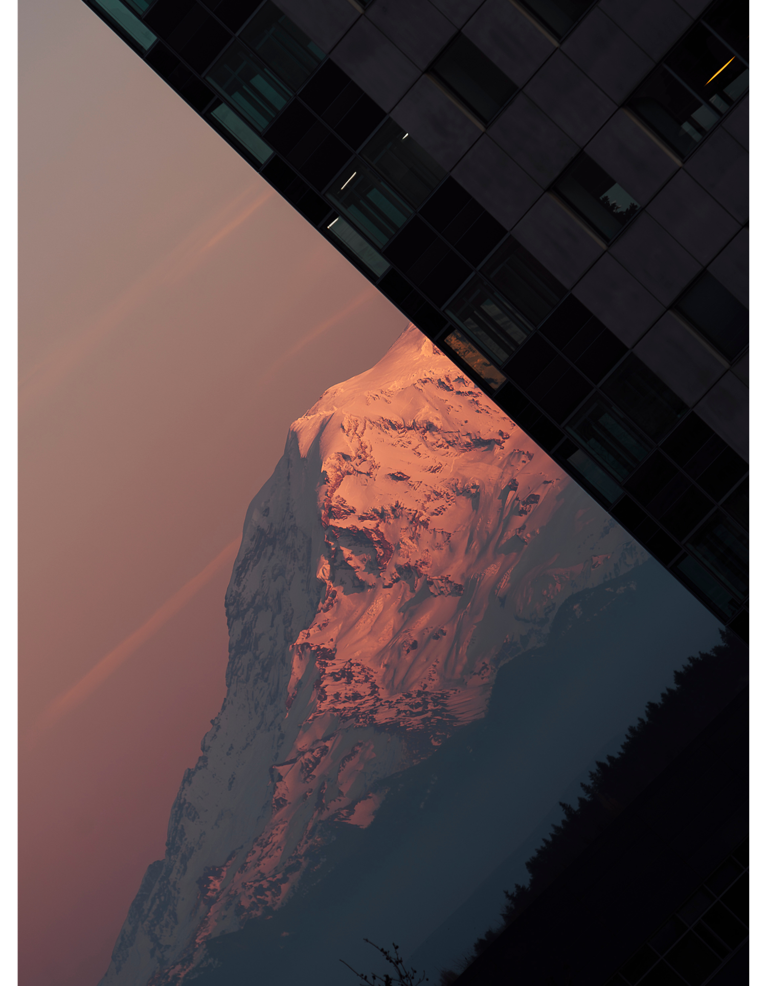 Dramatic mountain peak glowing orange during sunset against dark moody sky.