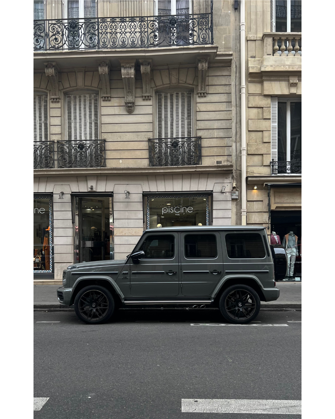 Grey Mercedes G-Class parked on classic Parisian street with ornate balconies and architecture.