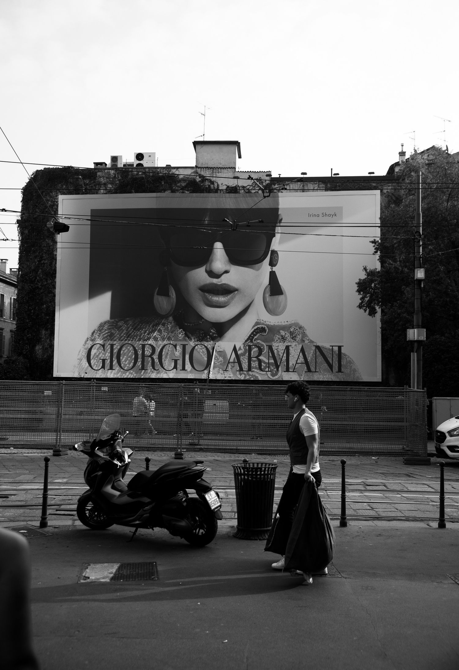 Black and white street scene with Giorgio Armani billboard and parked motorcycles. Milan, Italy.