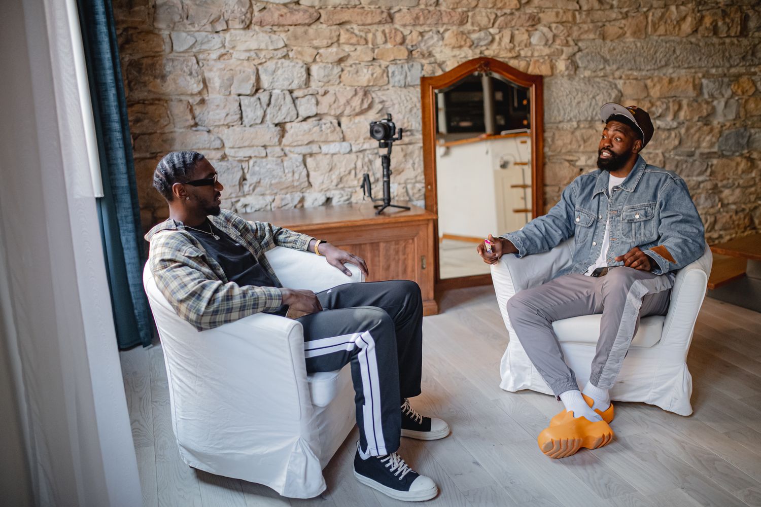 Two individuals having an animated conversation in a modern room with exposed brick walls.
