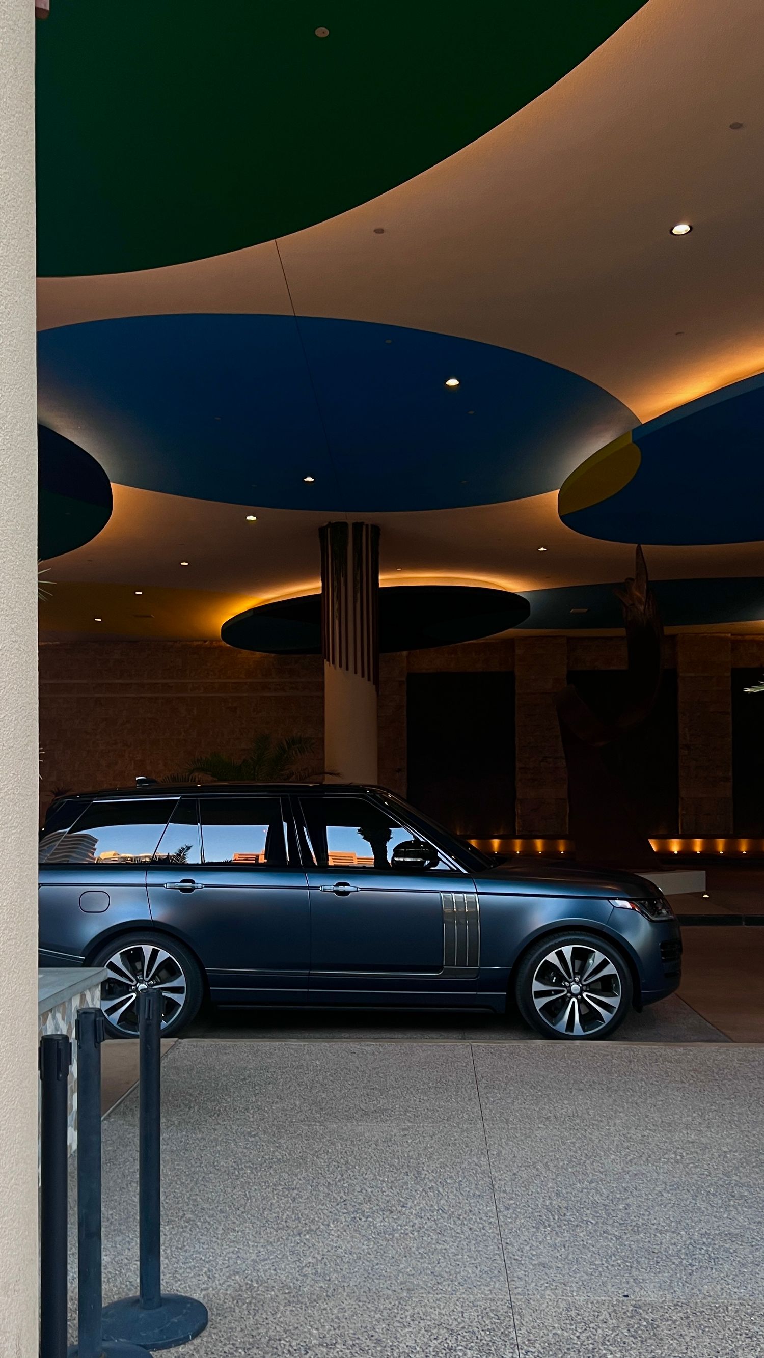 Range Rover SUV showcased under dramatic curved ceiling with modern architectural lighting.