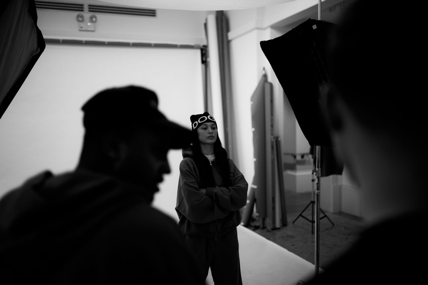Behind-the-scenes photo of a photography studio setup with lighting equipment and silhouetted figures.