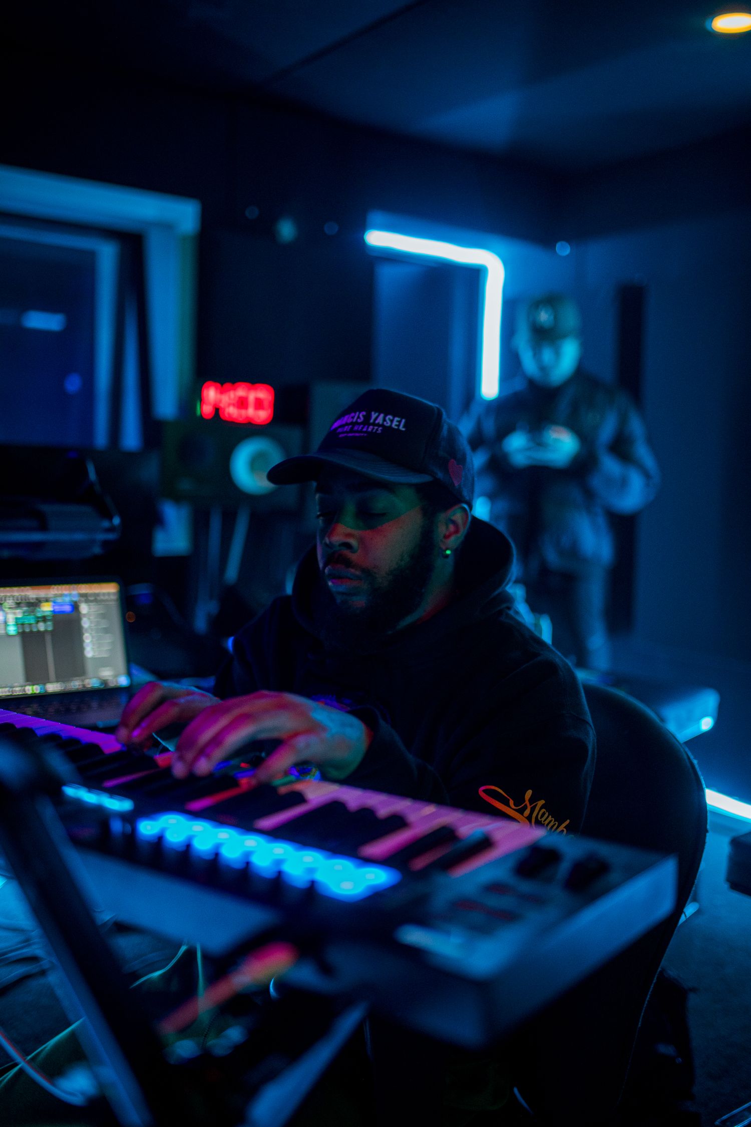 Music studio setup with blue neon lighting and electronic keyboards in dark room. Los Angeles.