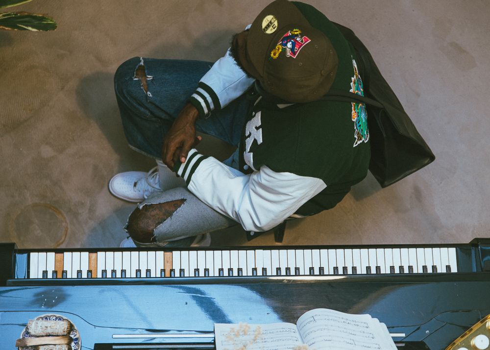 Overhead view of someone playing piano keys while wearing a baseball cap.