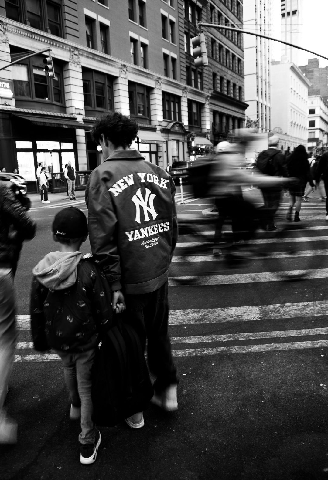 Black and white street photo of Yankees fans walking in New York City.