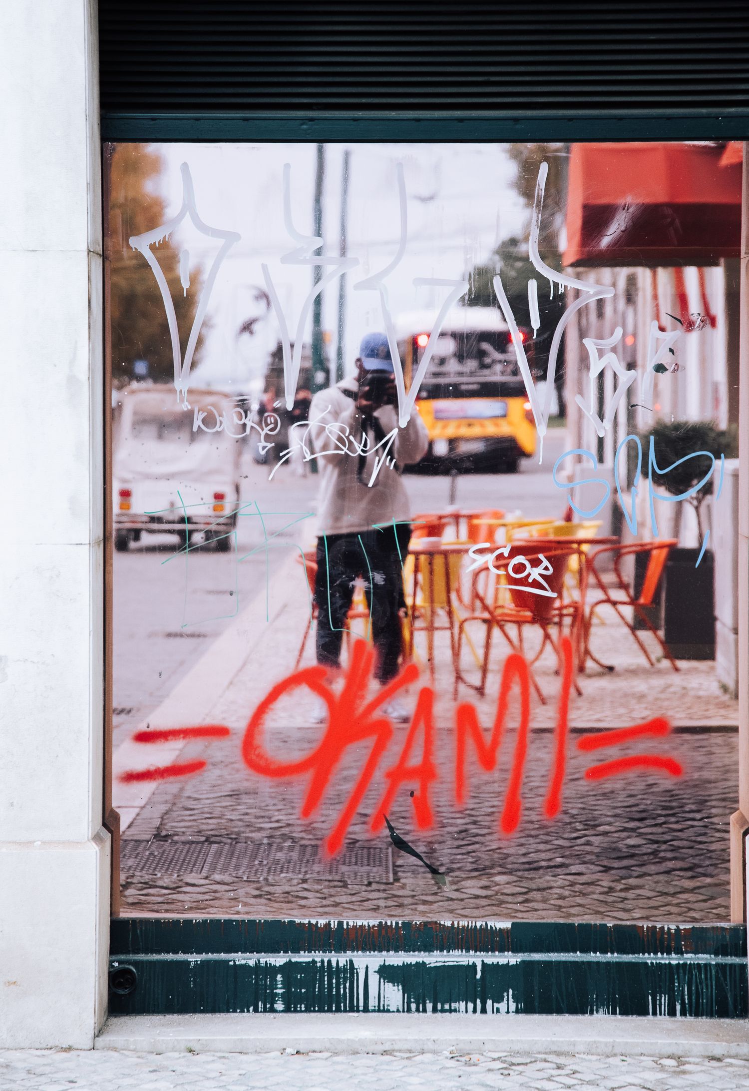 Urban street scene with red graffiti text painted along a white wall.