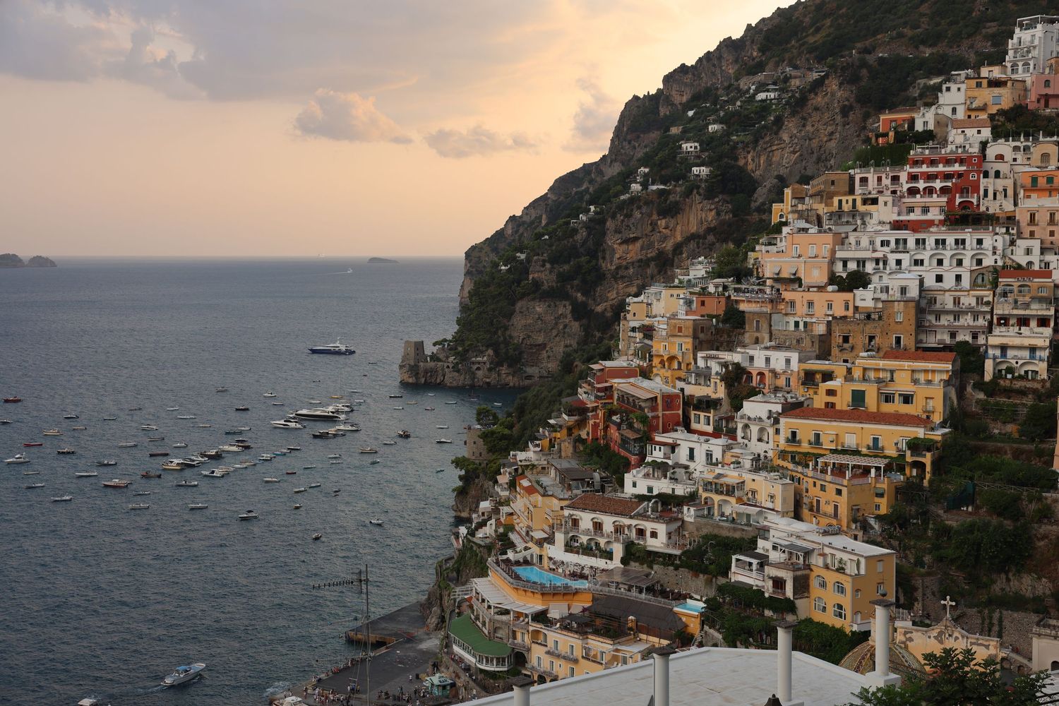 Picturesque view of Positano's hillside buildings overlooking the Mediterranean Sea at sunset.