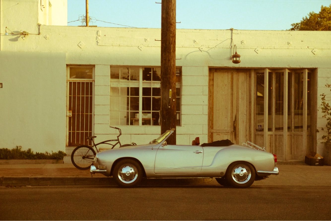 Vintage sepia toned photograph of a classic white car parked outside a commercial building. Santa Monica, California.