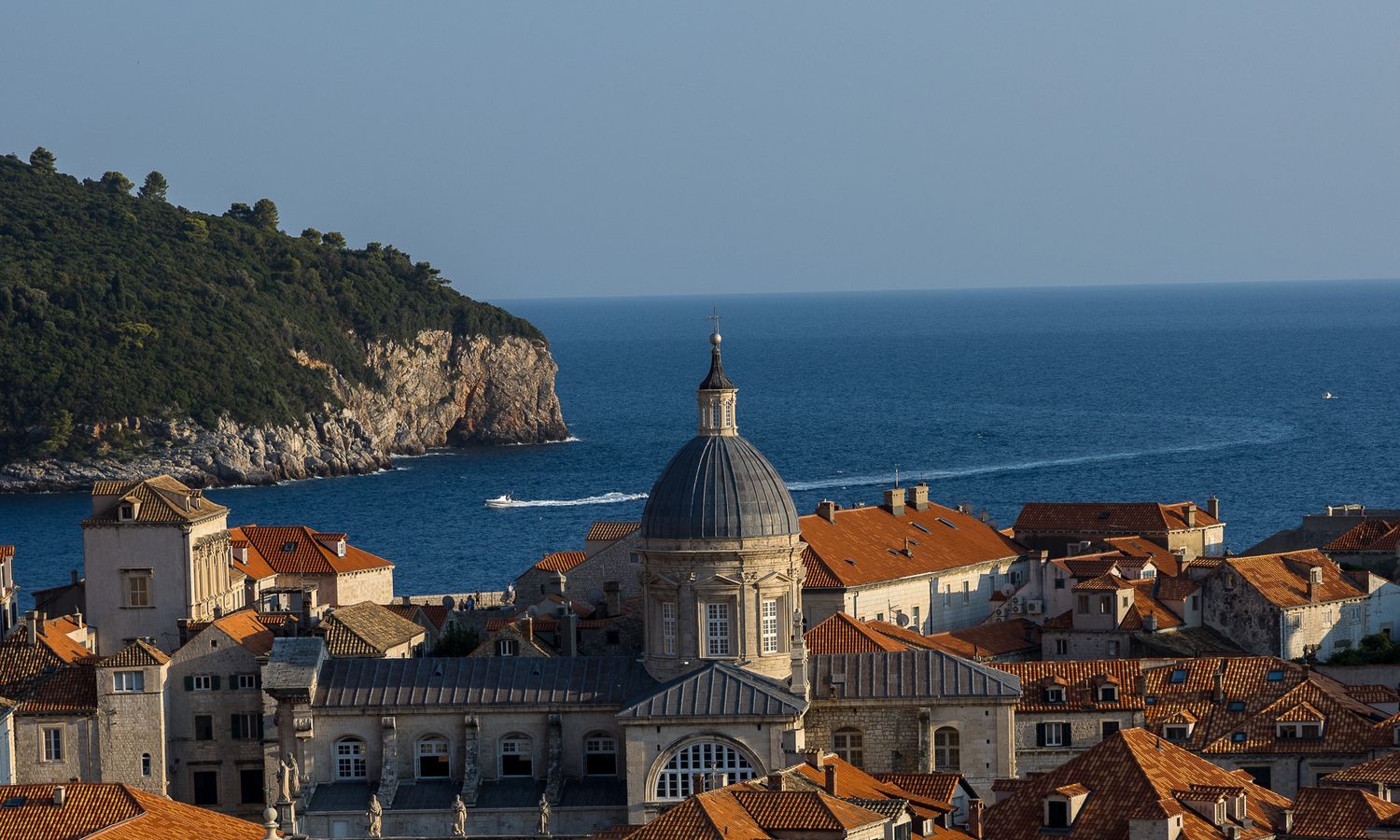 Scenic view of Dubrovnik's orange rooftops and cathedral dome against the Adriatic Sea.